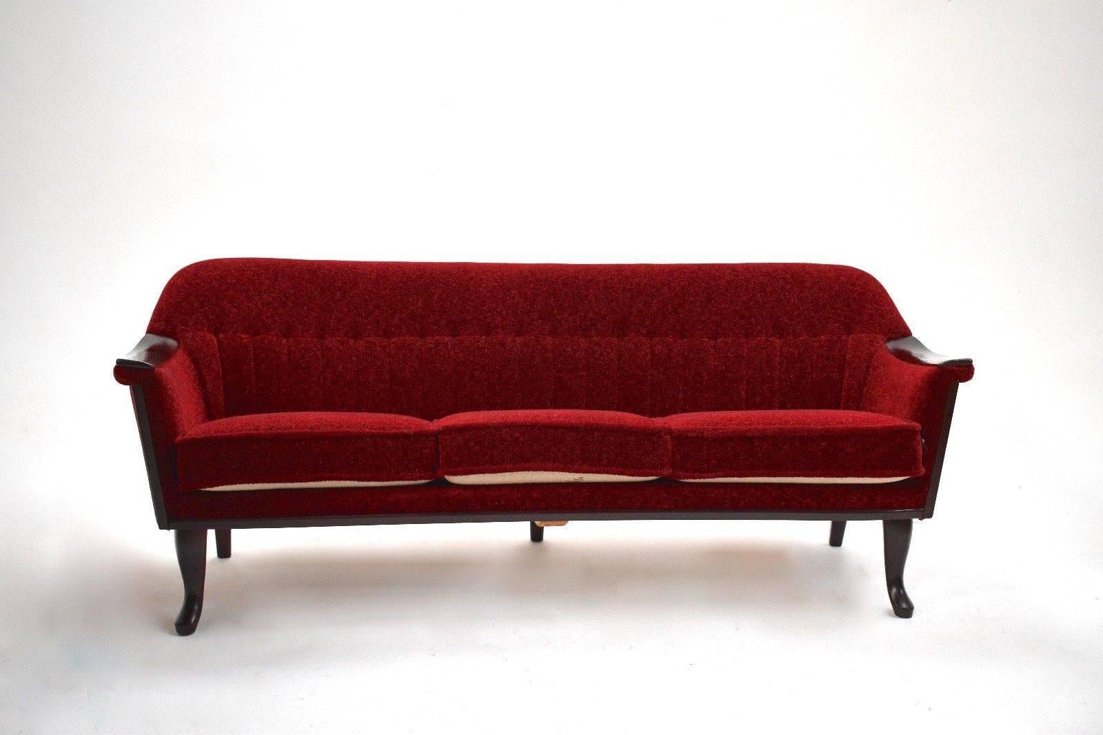 A beautiful Norwegian red fabric three-seat sofa, this would make a stylish addition to any living or work area. The sofa has a curved backrest and sculptured mahogany armrests for enhanced comfort. A striking piece of Classic Scandinavian