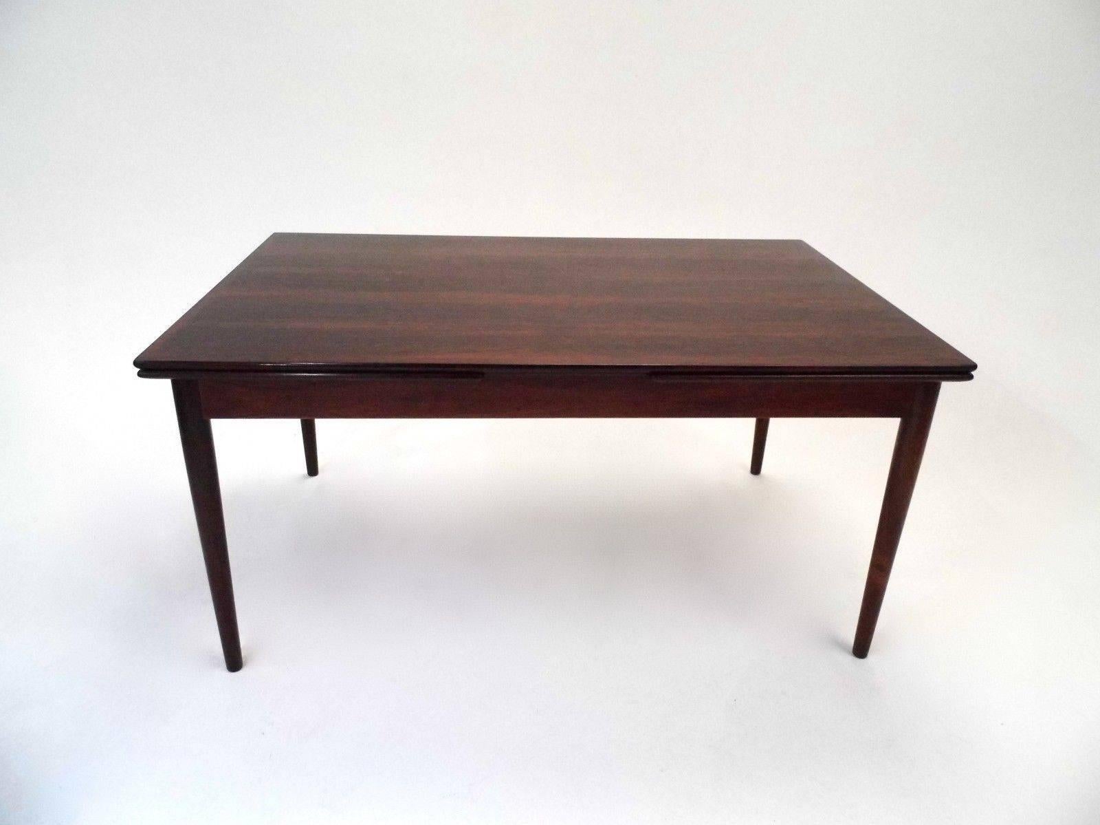 A beautiful Danish rosewood extending dining table, this would make a stylish addition to any dining area. The table has two extension panels which fit discreetly below the top panel and can be pulled out when needed. A striking piece of classically