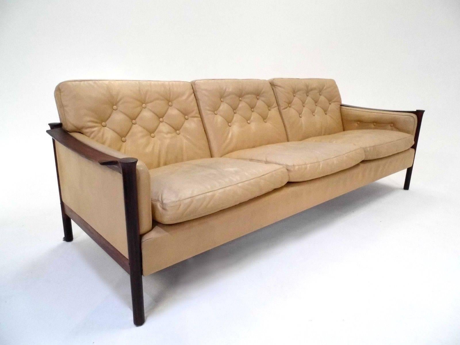 A beautiful Norwegian cream leather and rosewood three-seat sofa designed by Torbjørn Afdal, this would make a stylish addition to any living or work area. The sofa has buttoned cushions and sculptured armrests for enhanced comfort. A striking piece