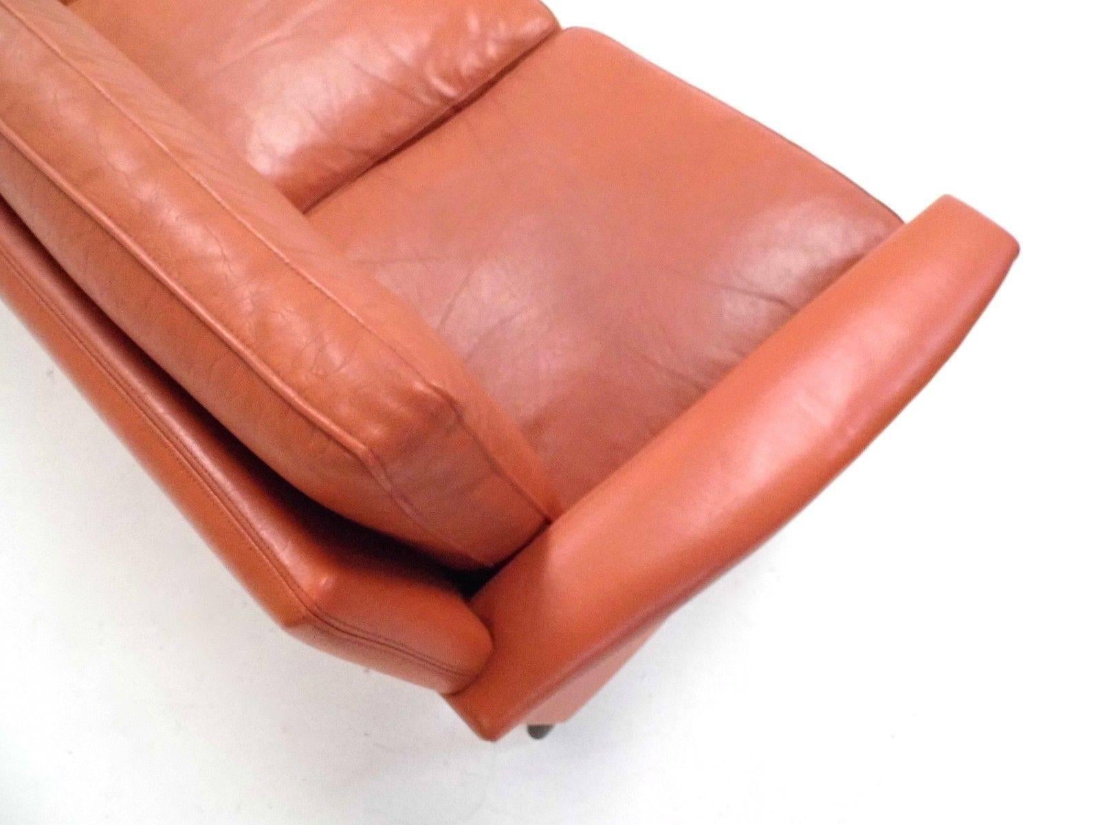 A beautiful Danish orange tan leather three-seat sofa, this would make a stylish addition to any living or work area. The sofa has wide cushions and sculptured padded armrests for enhanced comfort. A striking piece of Classic Scandinavian
