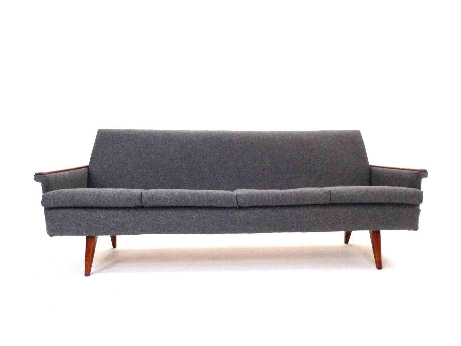 A beautiful Norwegian dark grey wool and teak four-seat sofa, this would make a stylish addition to any living or work area. The sofa has a high padded back and sculptured armrests for enhanced comfort. A striking piece of classic Scandinavian
