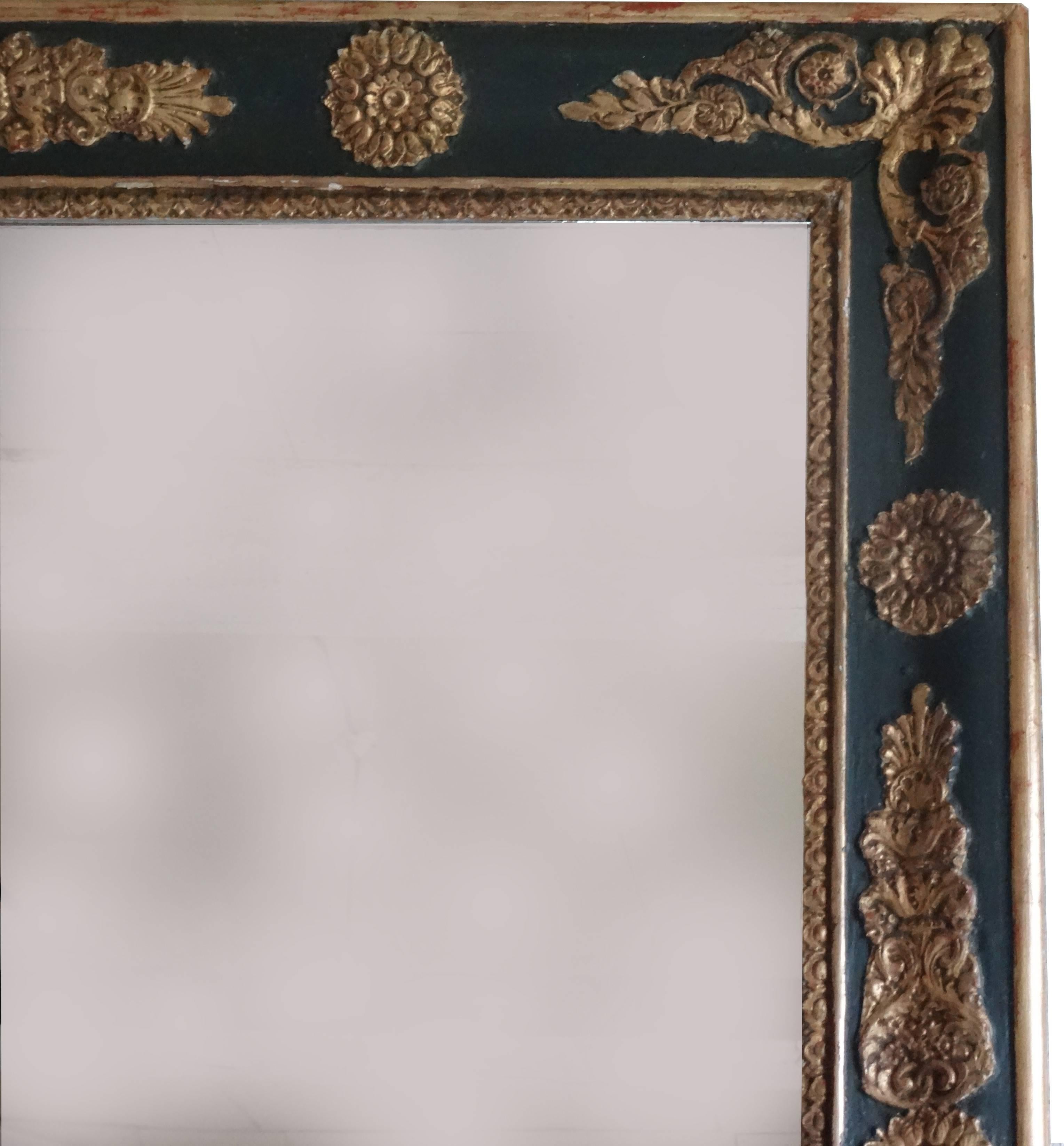 19th century Empire style French antique mirror. The wooden frame is in it’s original, black paint, with gilded Empire ornaments. The original plate is softly aged. The frame under, shows that this mirror is made to be on top of a fireplace, wall