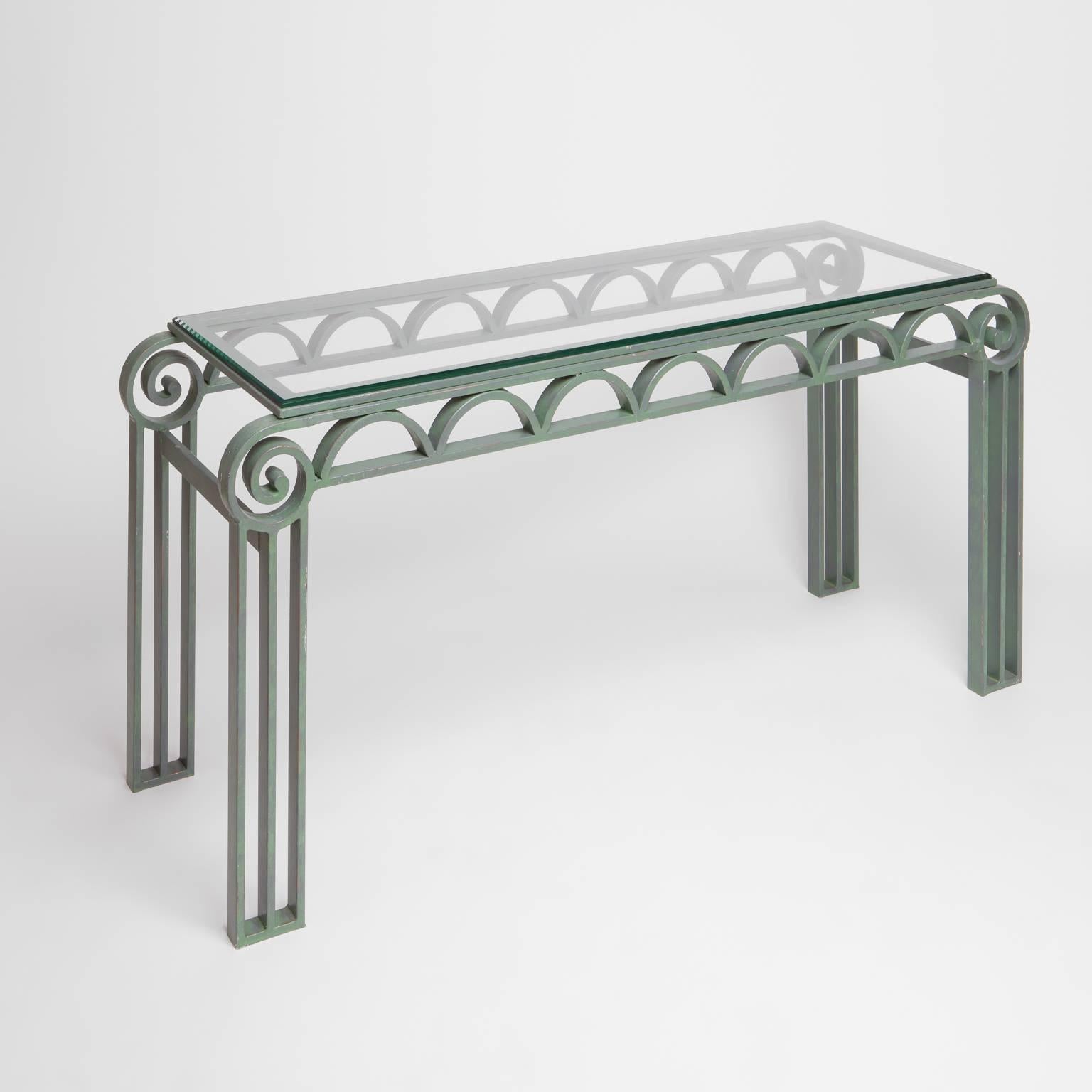 Art Deco style iron console table with glass top. Green painted iron with column legs meeting scrolled corners and half moon apron. Glass top.
   
