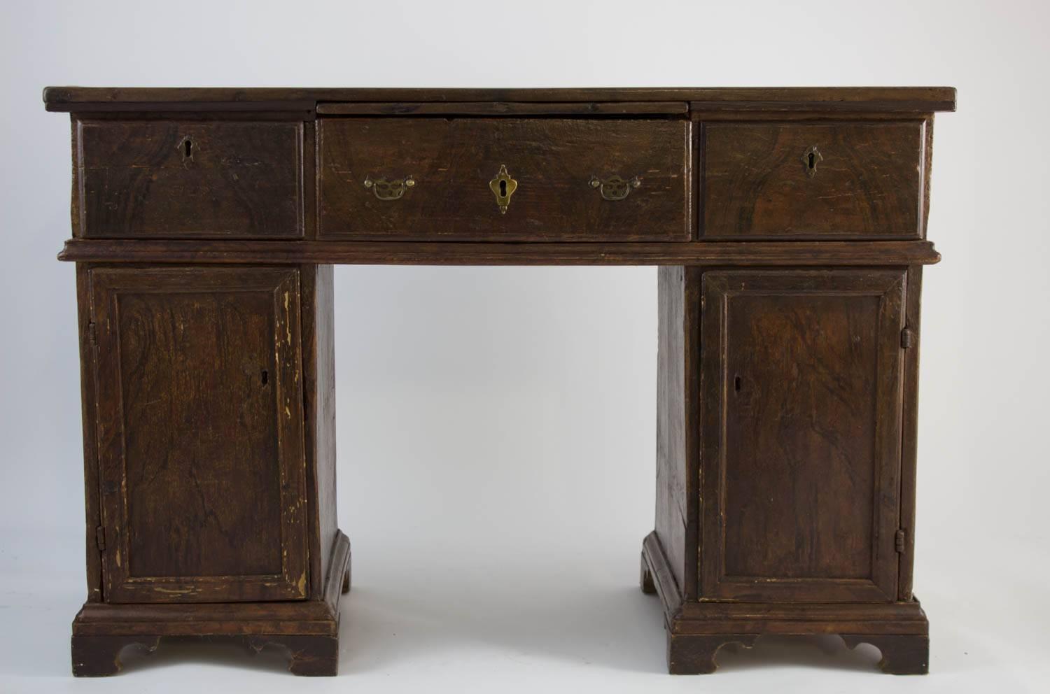 Grain-painted English pine kneehole desk, probably late 19th century, from the collection of Michael S. Smith. This is a well constructed desk with generous storage/shelving. Outside finish is in original grain-painted finish. It sits higher than