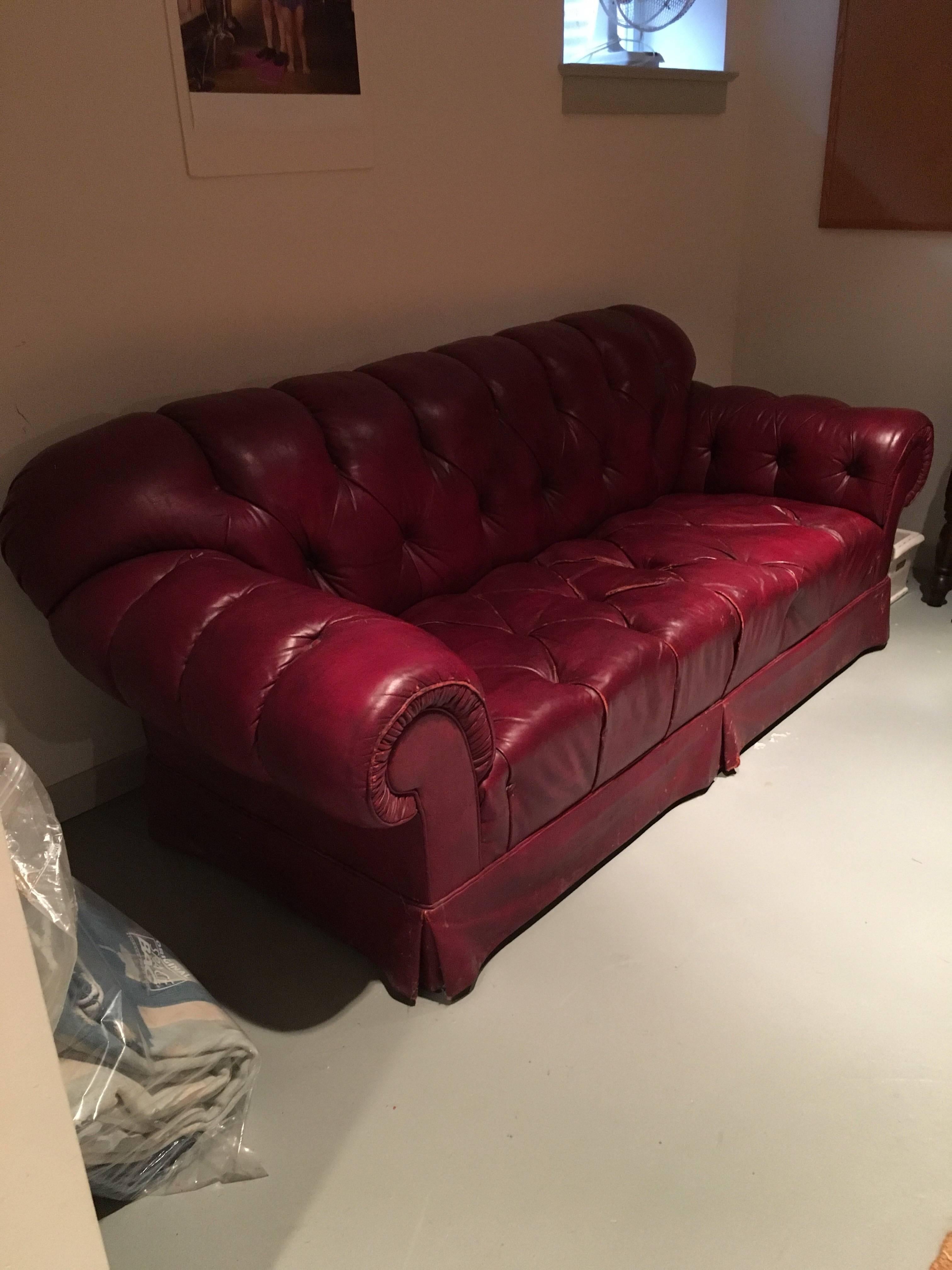 Chesterfield sofa in burgundy tufted leather with gathered rolled arms. Very comfortable sofa as is. The leather has wear and ripped in some spots. Priced to move.