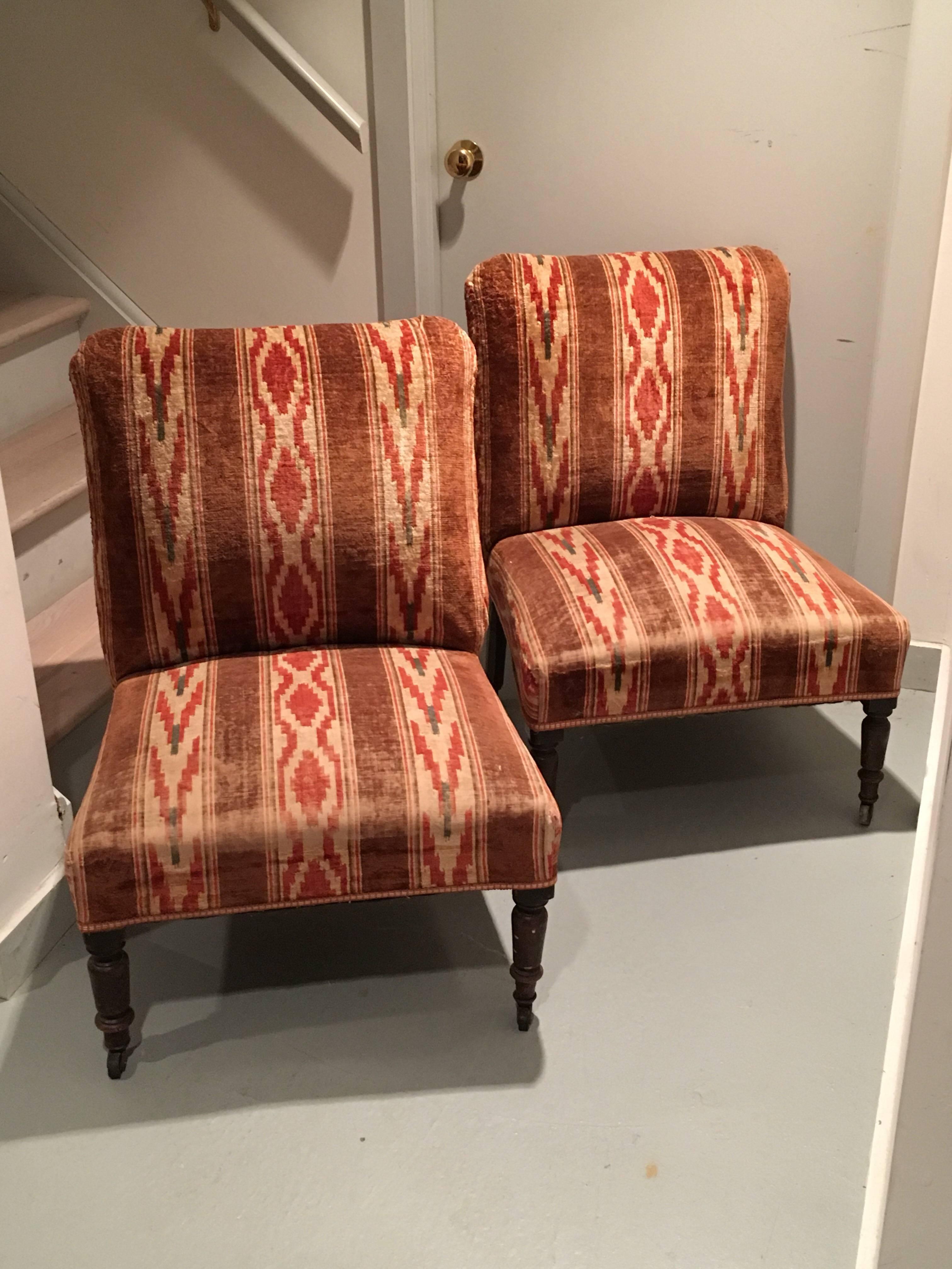 Pair of English velvet upholstered slipper chairs with rounded Turkish corners. Wear to the vintage velvet stripe on the seat edge. Great patina and look. Small tape trim applied around base perimeter. Legs on working original casters.