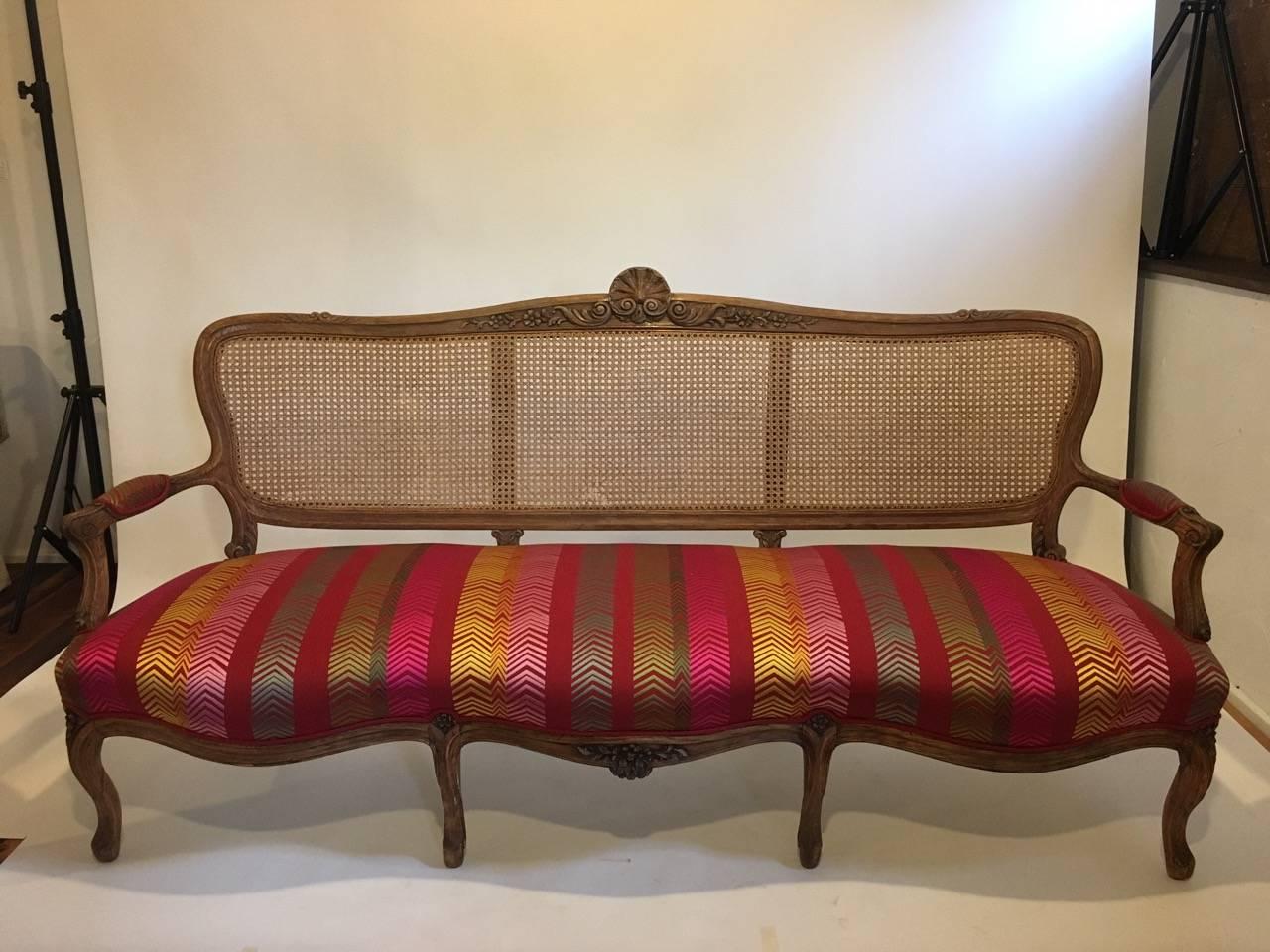 French caned back settee reupholstered in Christopher Farr fabric "Bookend".

Measures are 74" W x 38.5" H x 23" D x 17" sh.