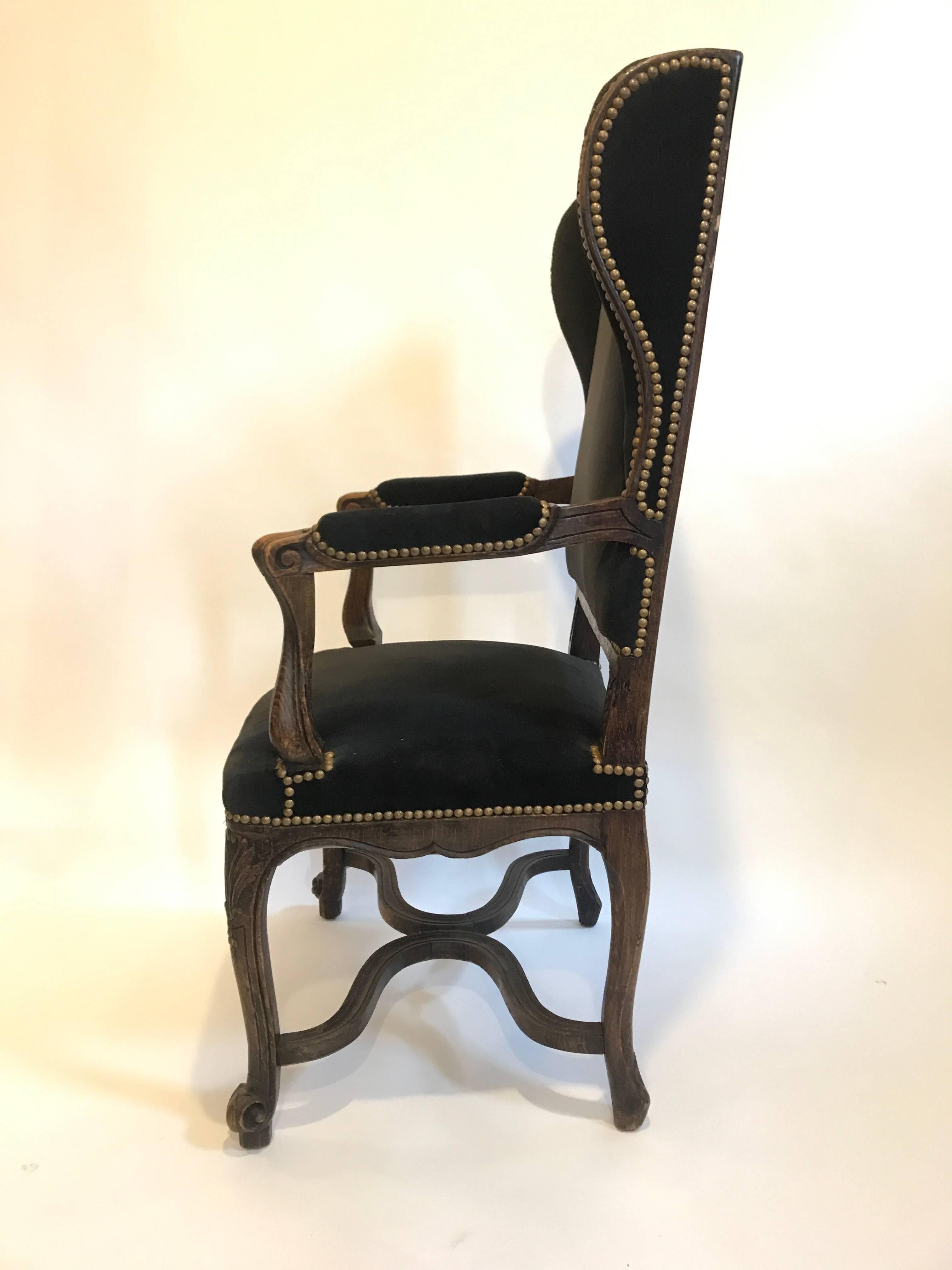 19th century Louis XV style wing chair with cabriole legs, black velvet upholstery and brass nailheads. This wing chair is more unusual in its scale. It has a slightly higher seat height for a wing chair at 17