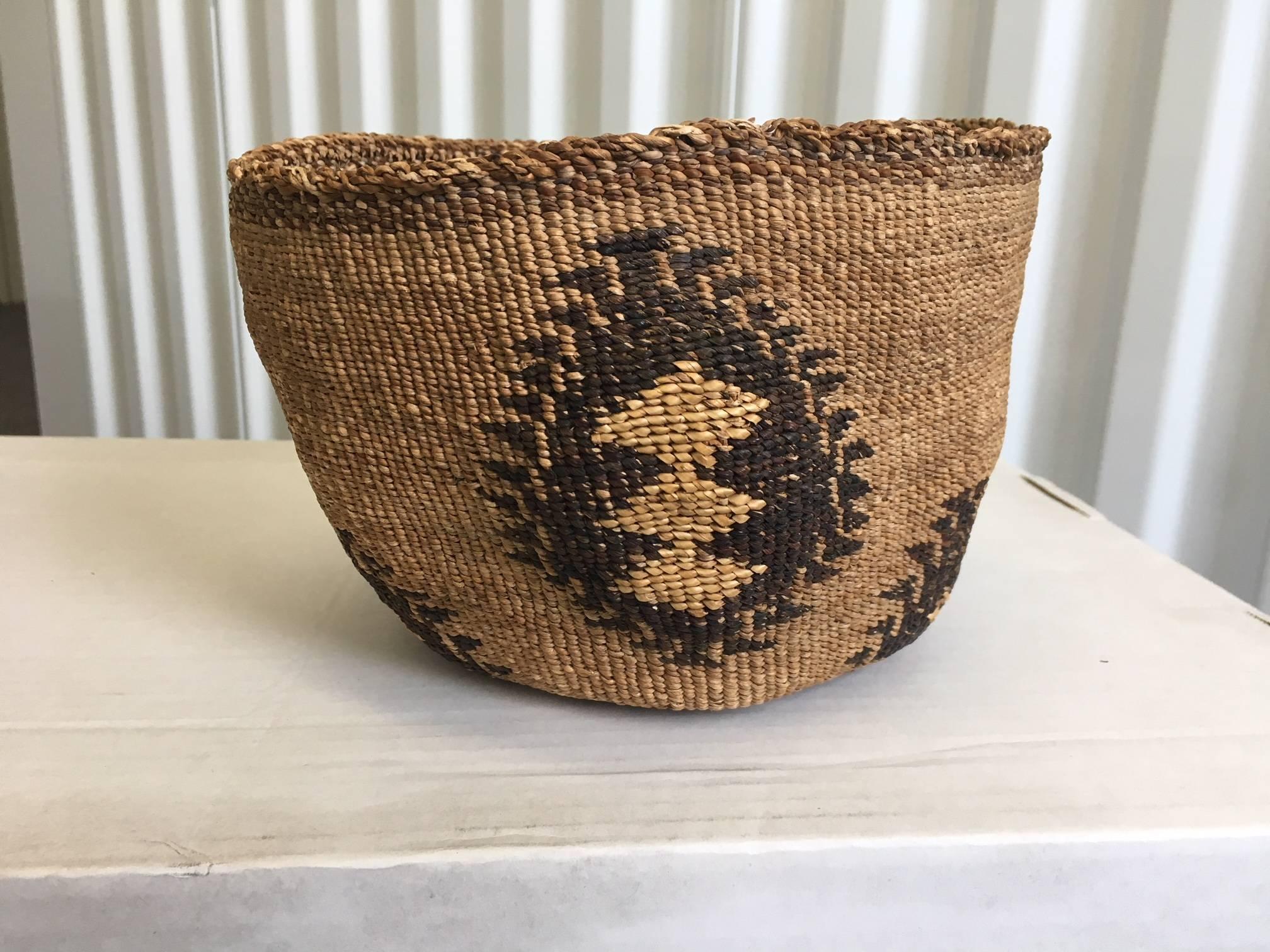 Native American Klamath basket. This is a soft and pliable basket with triple triangle motif woven in tule and dyed tule in characteristic overlay weave. There is some loss around the rim edge and a slightly irregular shape on one side. Otherwise in
