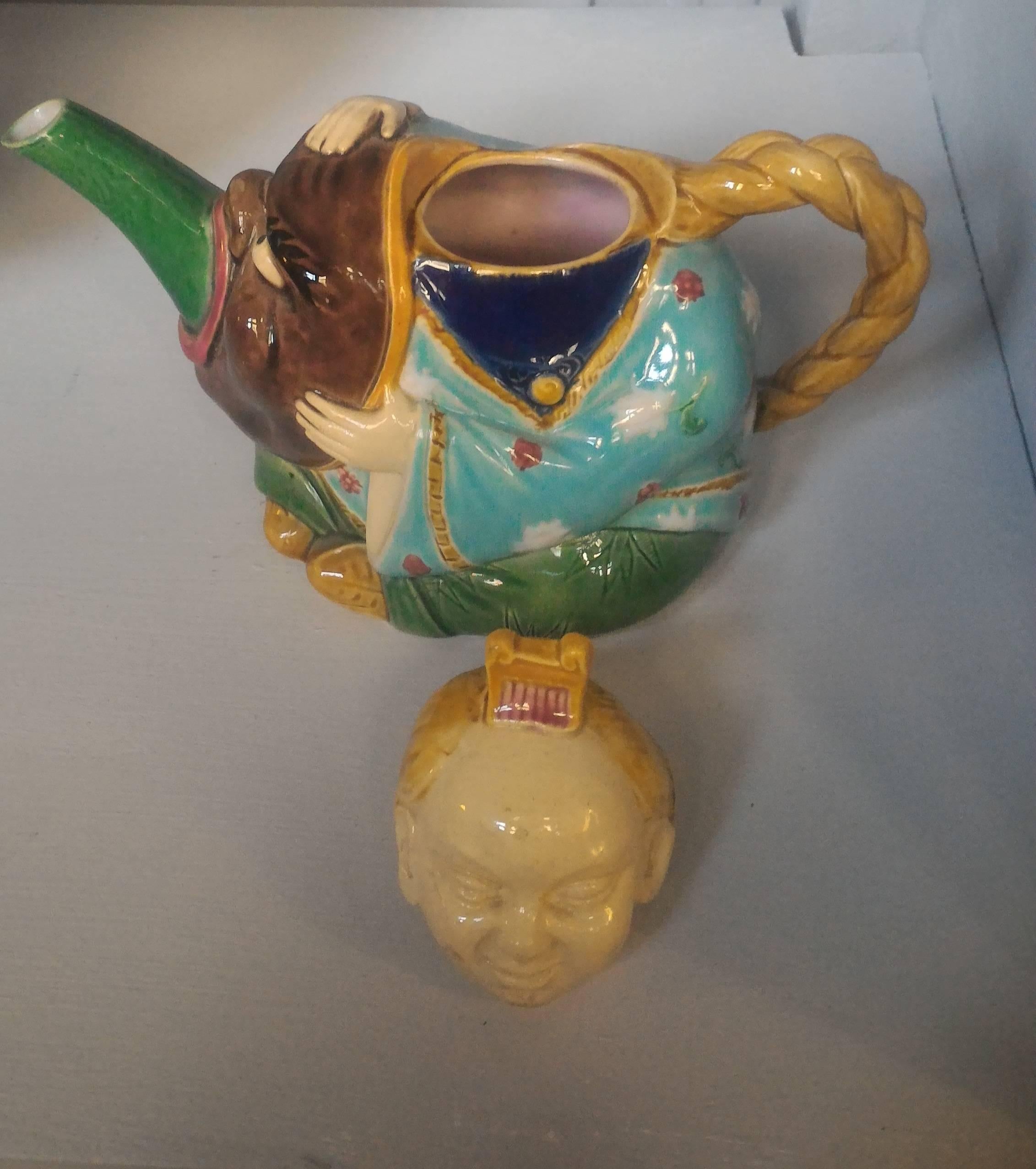 This charming little teapot realized by the famous manufactory of Minton in England, reflects all the influence of Orient on Decorative Arts of the second half the 19th Century. It can be seen a Chinese man in traditional costume, holding a mask in
