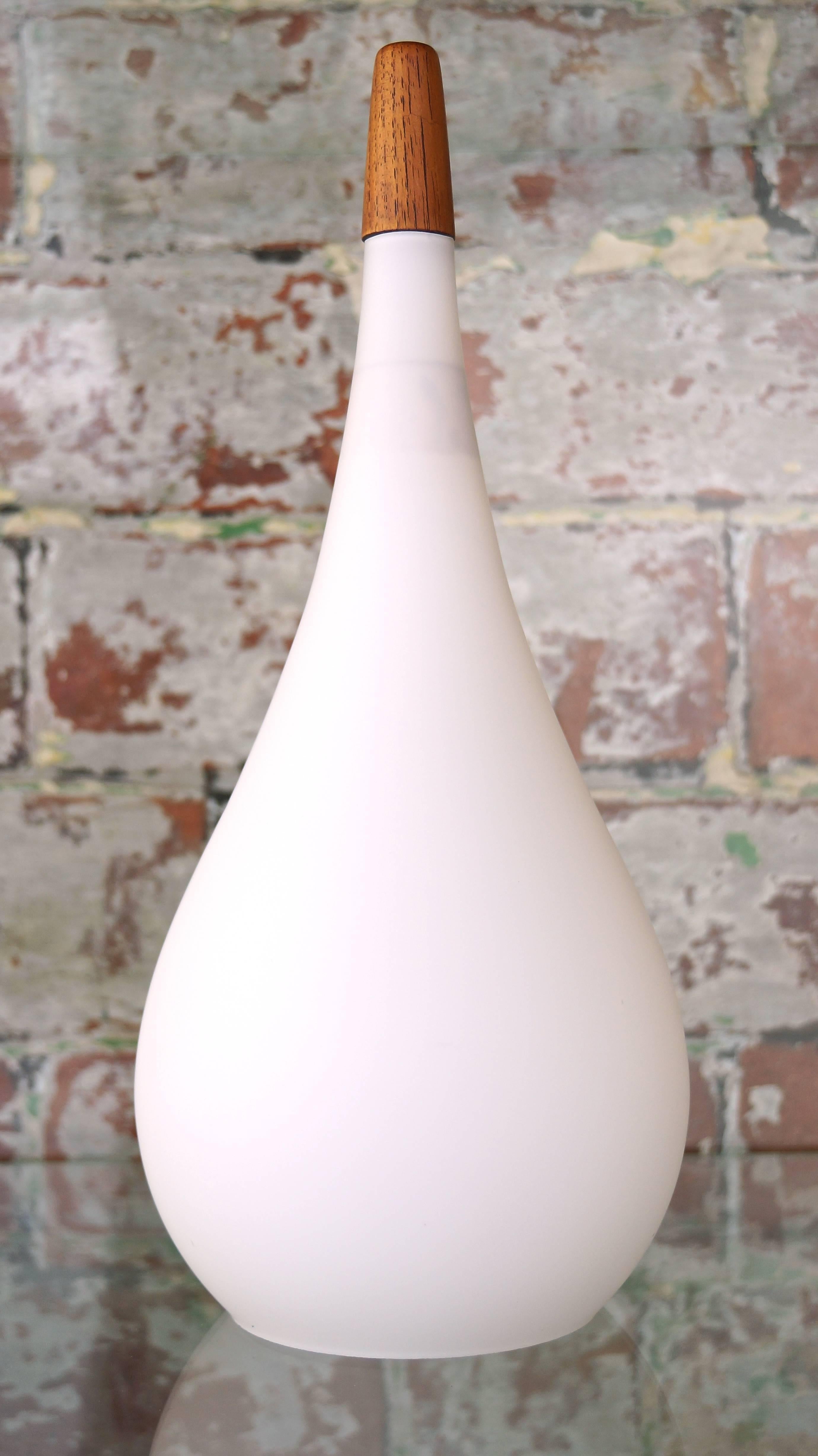 Vintage white glass pendant drop light with solid teak finial.
Designer: Holmegaard, Denmark,
circa 1960s.

A beautiful Danish handblown 1960s matte white glass pendant drop light by Holmegaard, circa 1960s.

Finished with a lovely solid teak