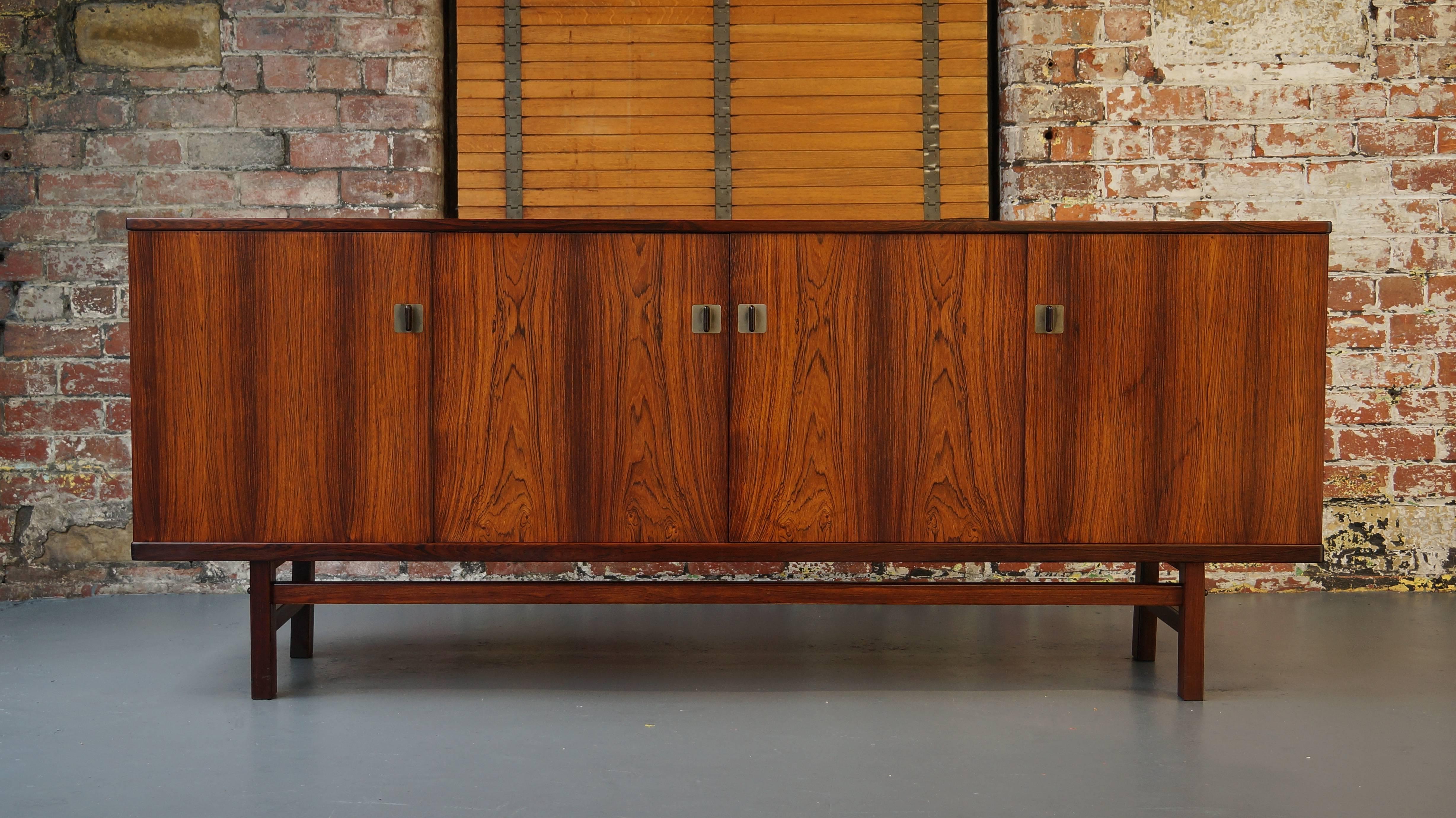 Exceptionally high quality Danish rosewood credenza or sideboard 
Designed by Nils Jonsson,
circa 1960s.

Featuring solid nickel bezel surrounds with beautifully shaped solid rosewood handles.

Contrasting pale maple interior with a flight of