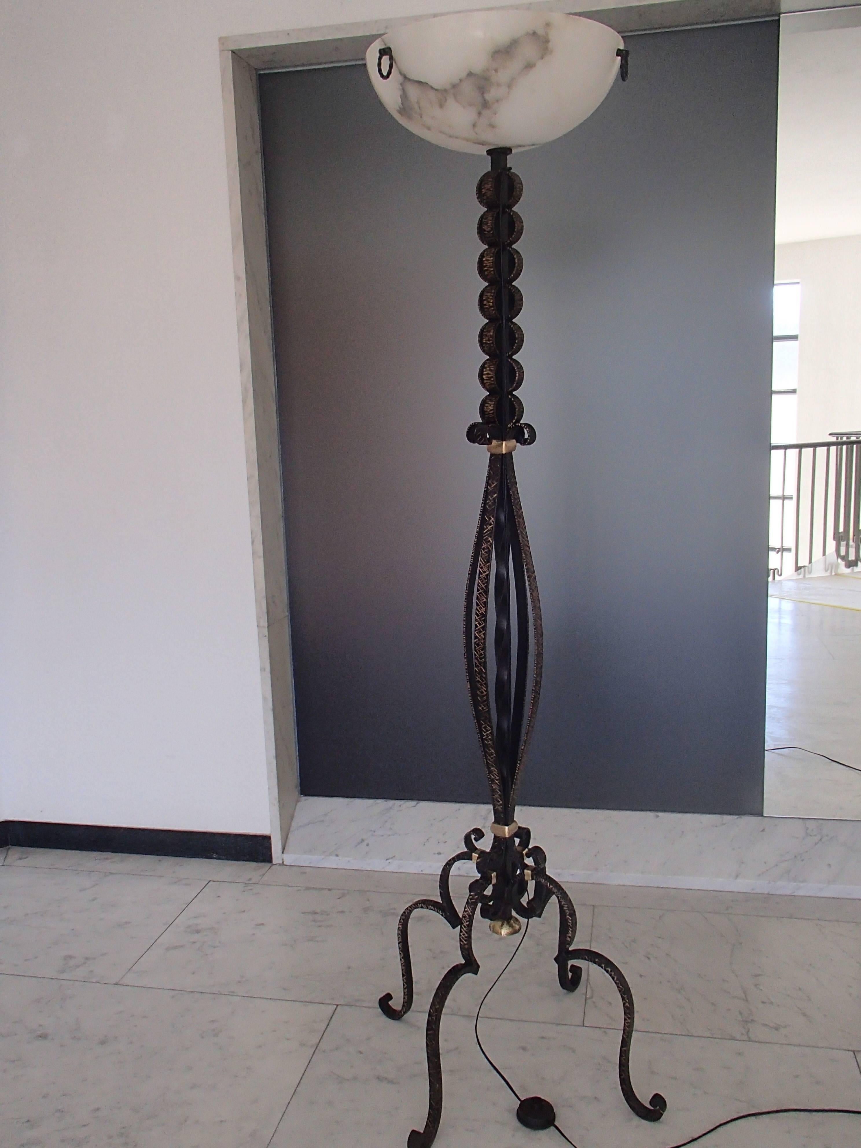 Decorative wrought iron floor lamp with brass elements and alabaster shade.