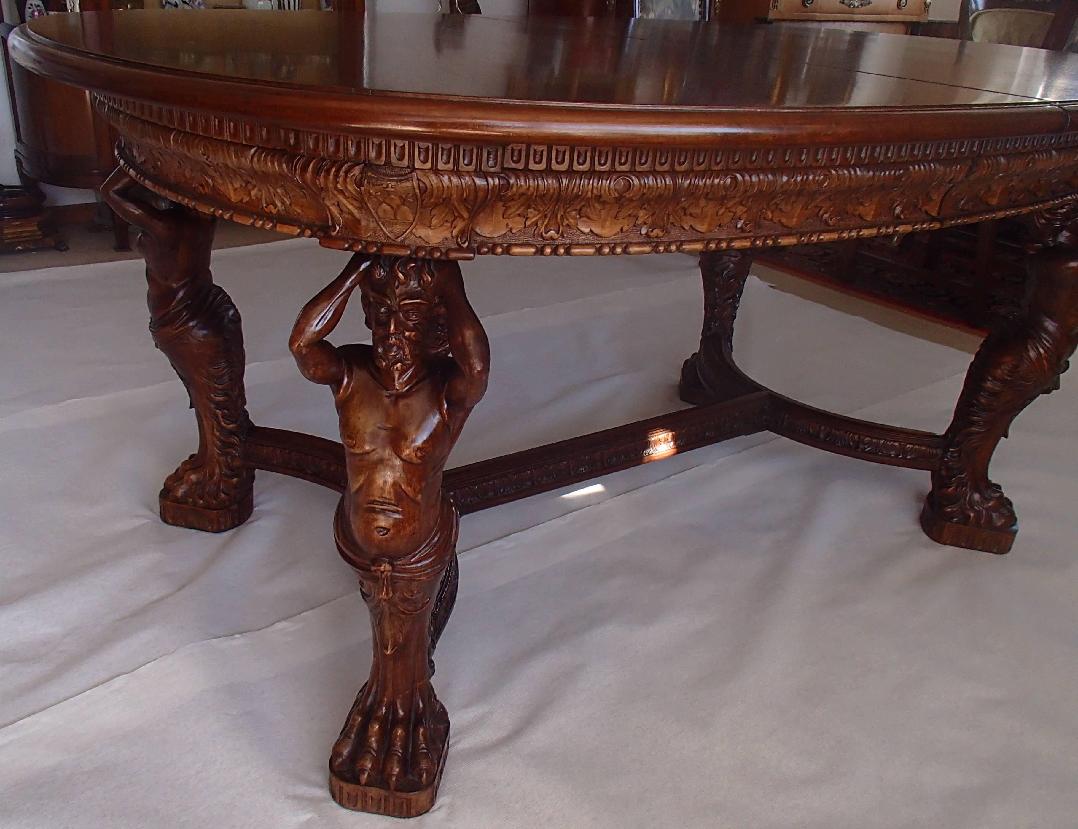 Hughes mahogany dining table with figurative sculpted legs carved details all-over around the table and between the legs. It comes with one small 45 cm and 6 x 65 cm large inlays which makes it 6 m long by 1.20 m large. The inlays are brut dark