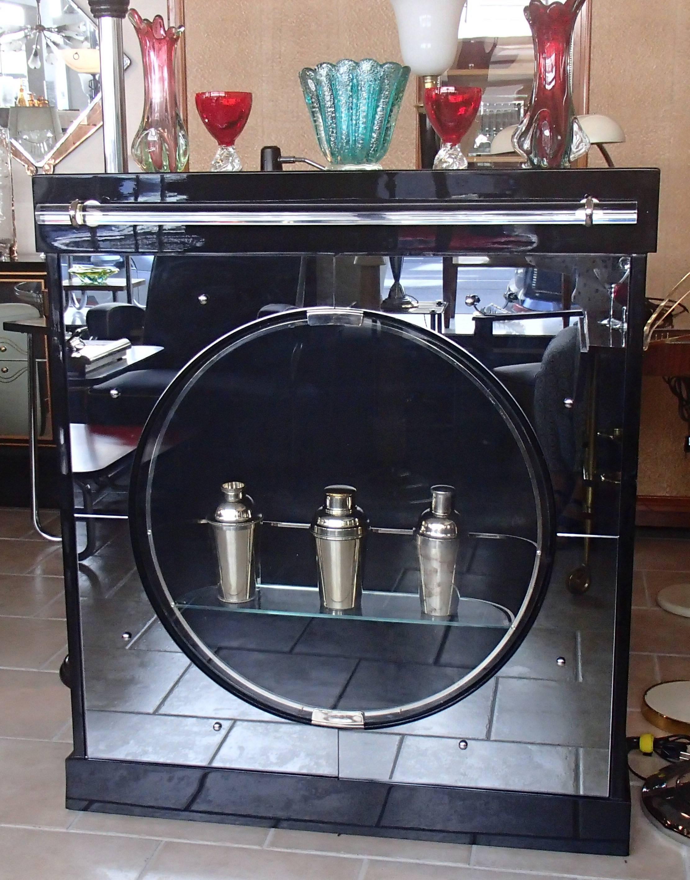 Black shell lacquered bar/drink cabinet restored with new anthracite mirror front and plexiglass handle and mirror top. The bull eye door is rotatable and the shelf is 63 x 11 cm . On both sides there are three small shelf's inside.