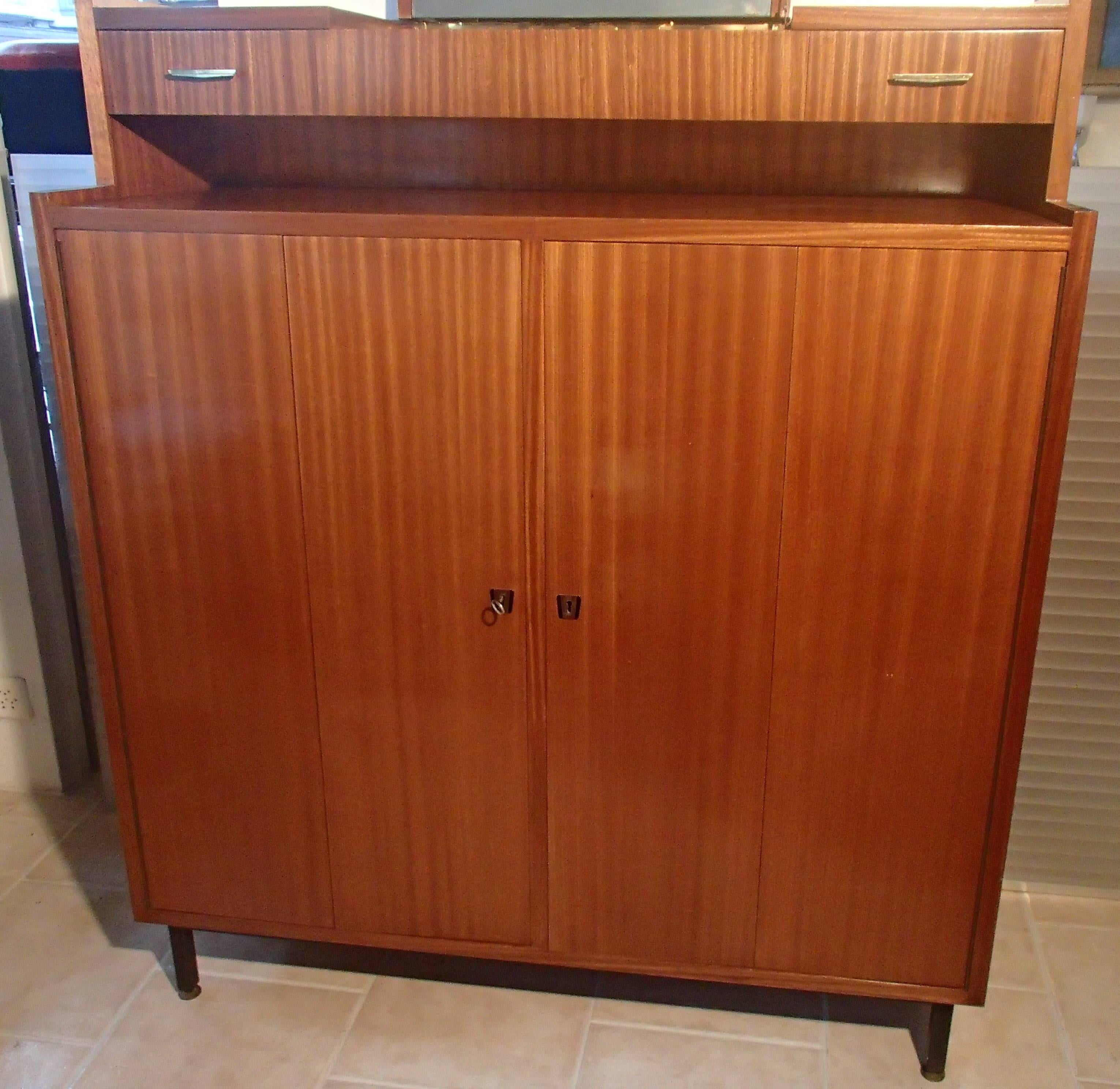 Mid-Century gentlemen dresser with foldable doors. On the left side seven self's that can be pulled out and on the right side a range of five drawers. On the top two drawers and compartment with mirror.