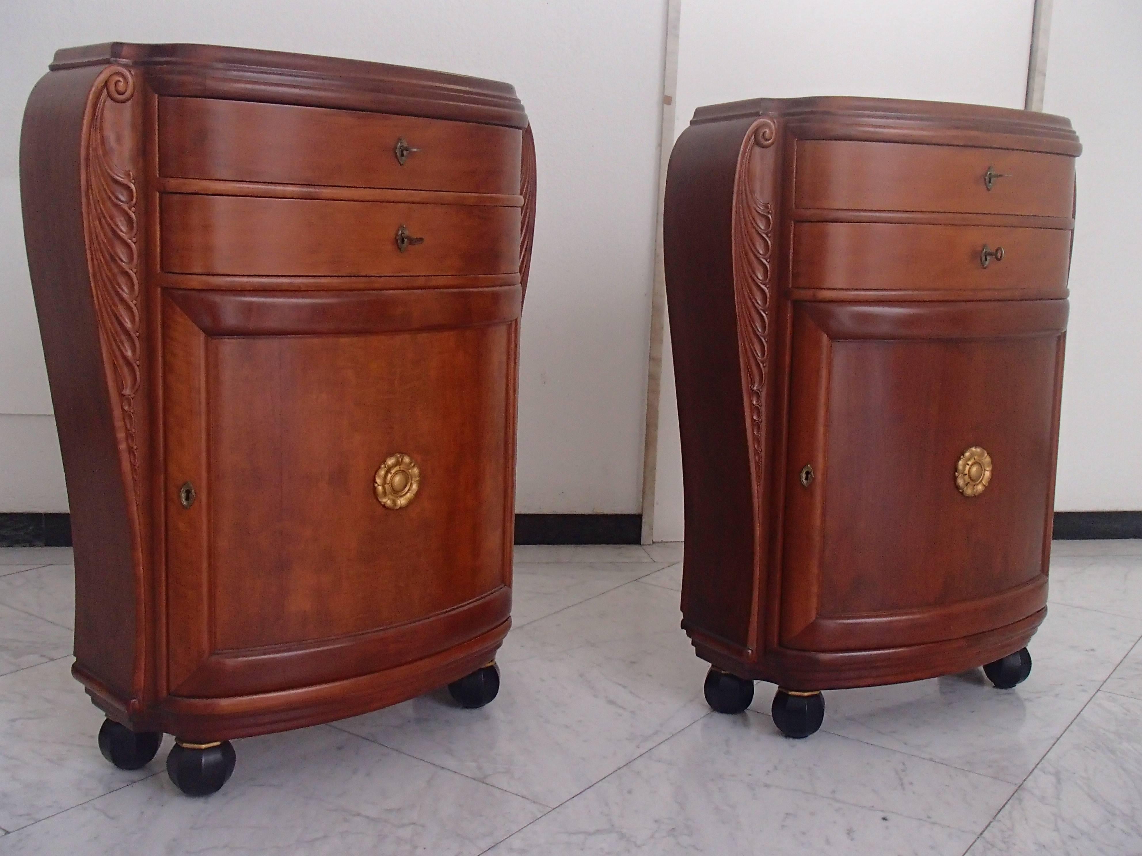 Very decorative pair of small cabinets/consoles/cupboard mahogany tinted birch.
Two drawers one door with inside one shelf beauty full carved side ornaments laying on four black and gold tinted round legs. Floral golden ornament on the door.