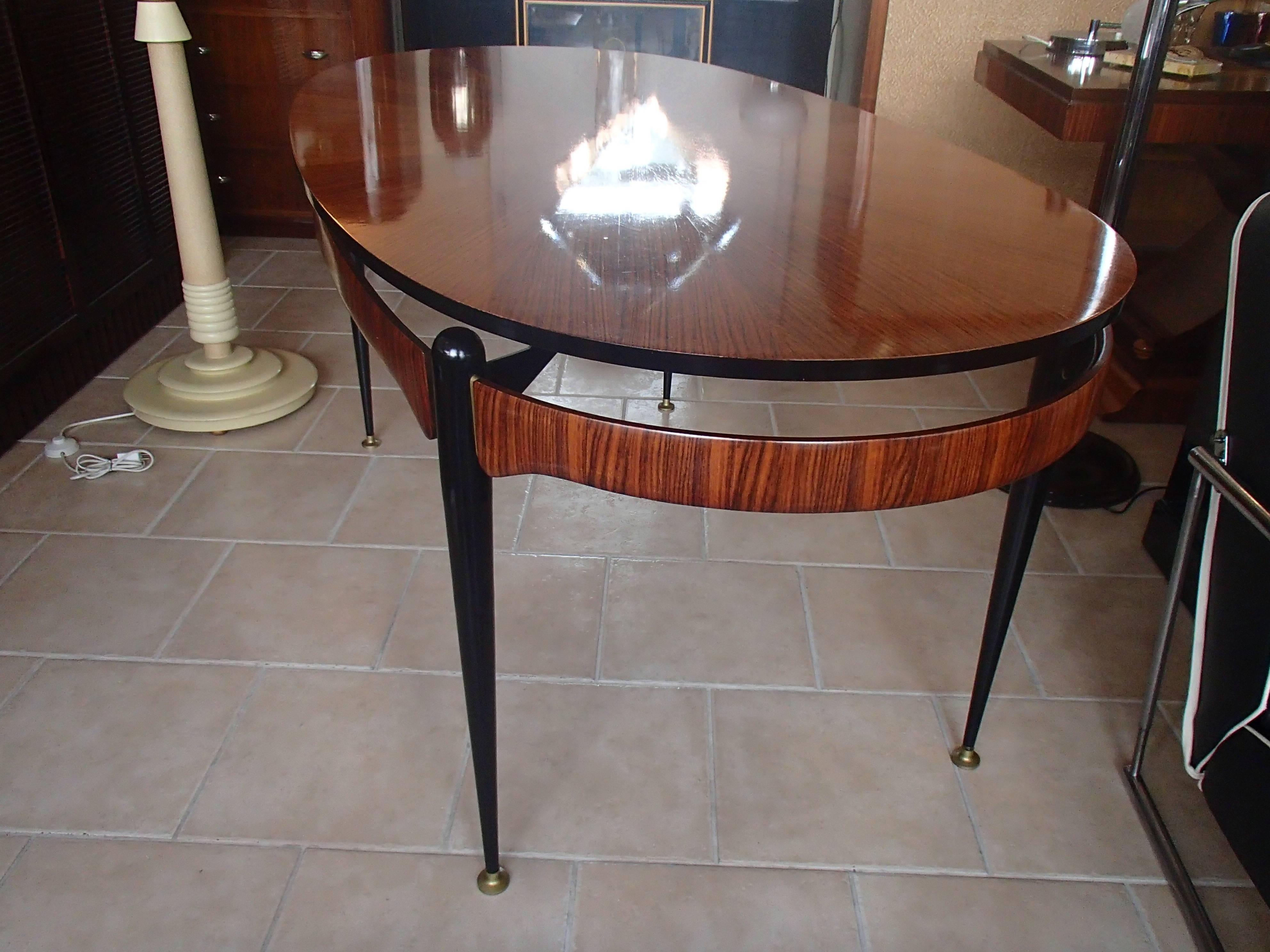 Very elegant rosewood dining table with black legs and brass ornaments.