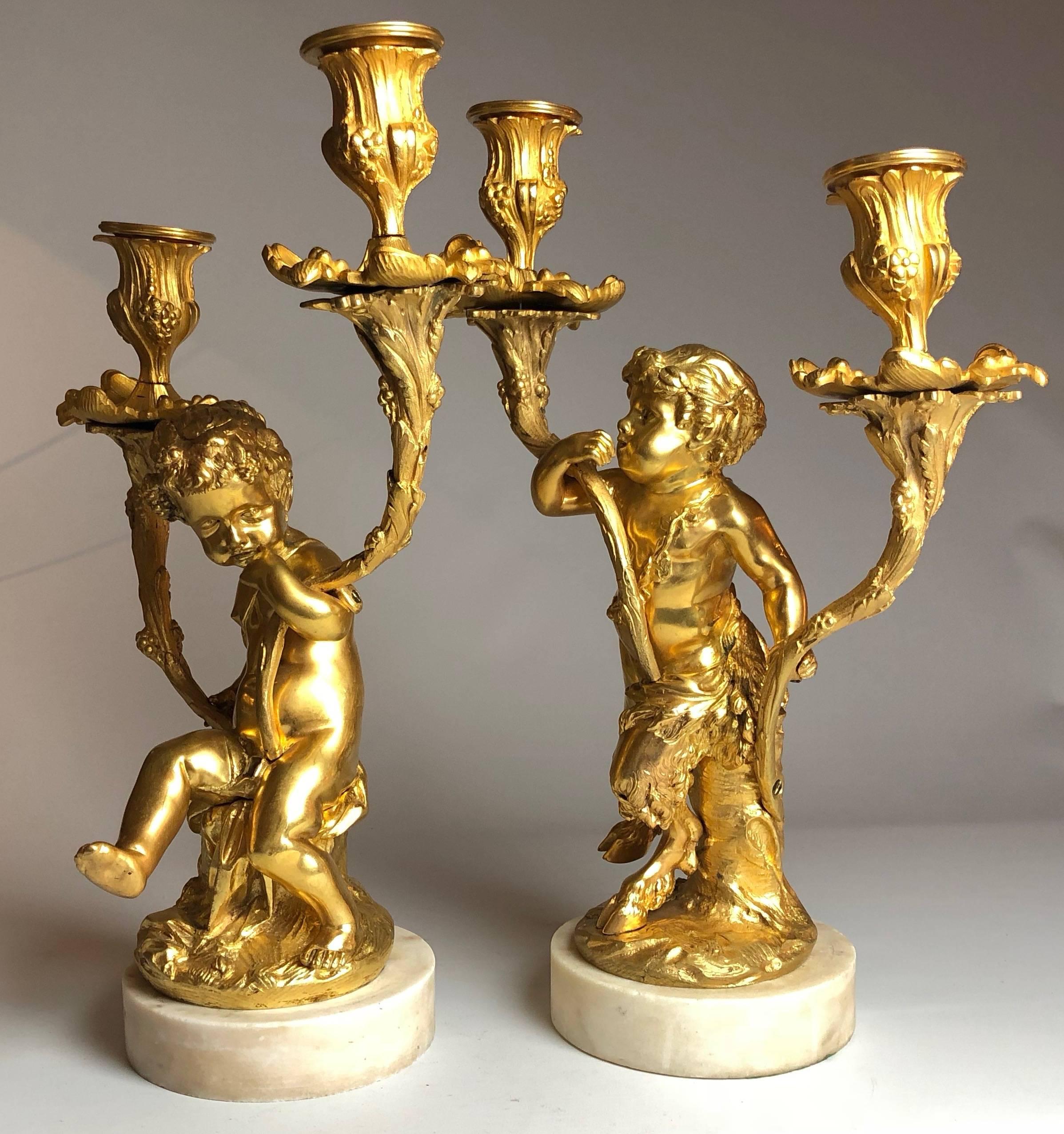 A pair of gilt bronze and white marble two-branch candelabra in the manner of Clodion.

They each stand 11" tall

France CIRCA 1860