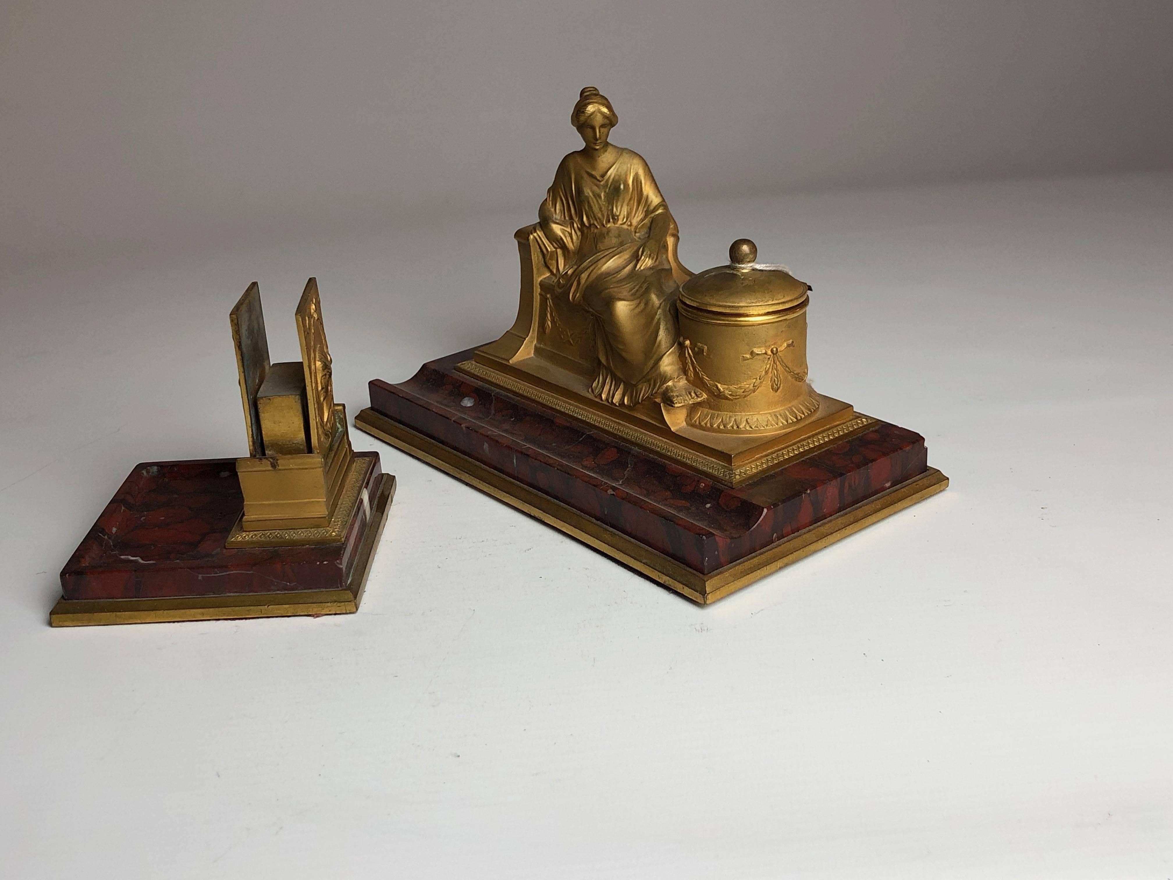 A lovely matching desk set comprising of a figural bronze inkwell with a matching match case and striker, both sat on reuge marble bases.
Signed on the rear of the inkwell 