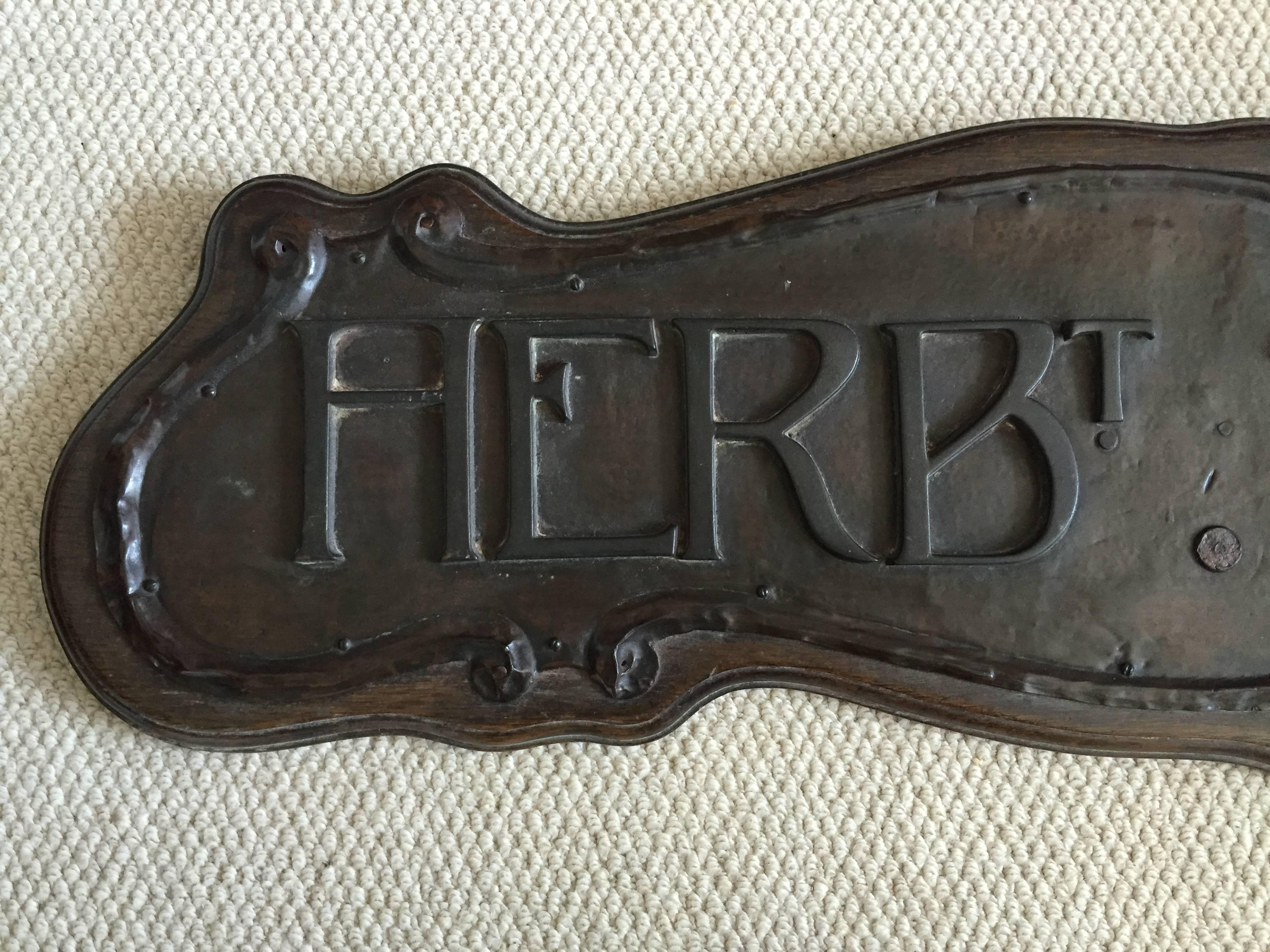 Unique handmade shop advertising panel "Herbert Thomas" formed of a curving oak backboard with iron hanging strips with a mounted copper hand beaten repousse panel set with heavily patinated letters. The piece is in full original condition