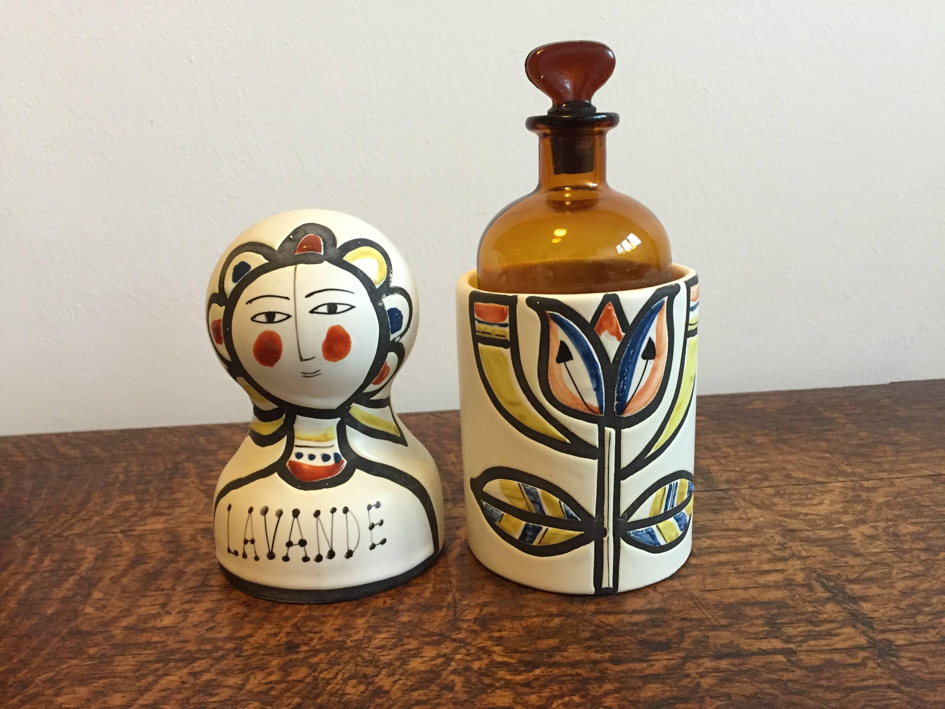 Scarce Roger Capron glazed and hand-painted ceramic vessel with a stylized design of a femme fleur containing an amber glass bottle within with original stopper. Dates to circa 1956. This is a very unusual piece in that it also has a monogram (the