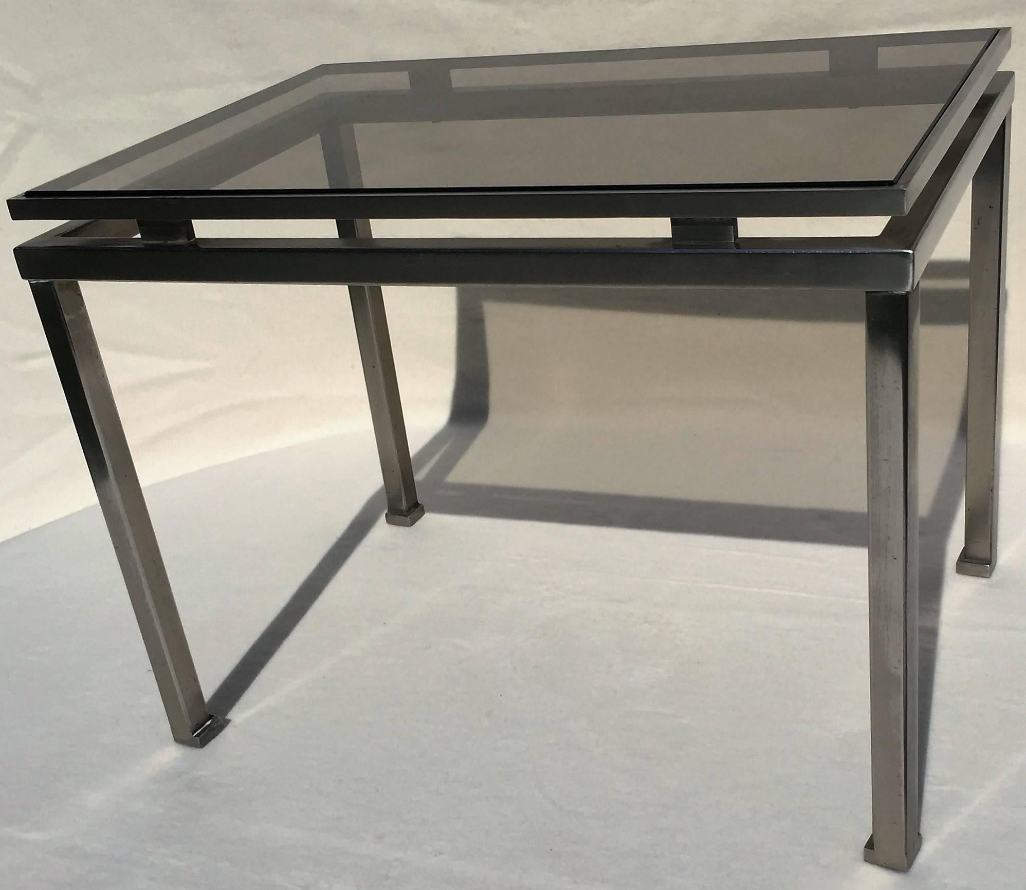 A brushed steel side table with a new smoked glass top designed by Guy Lefèvre for Maison Jansen, France, circa 1970.