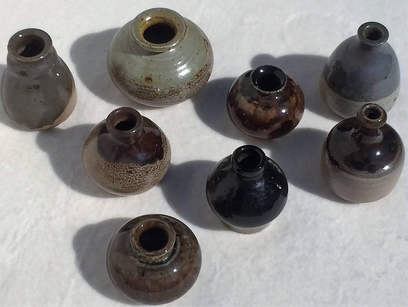 A set of eight unique turned ceramical miniature vases by Lilo Grinzoff-Assenmacher, Germany, 1960s. Salt glazed in glossy blue, grey, brown and cream. The salt glazed ceramic is burned at high temperatures and is extremely durable. 
The largest is