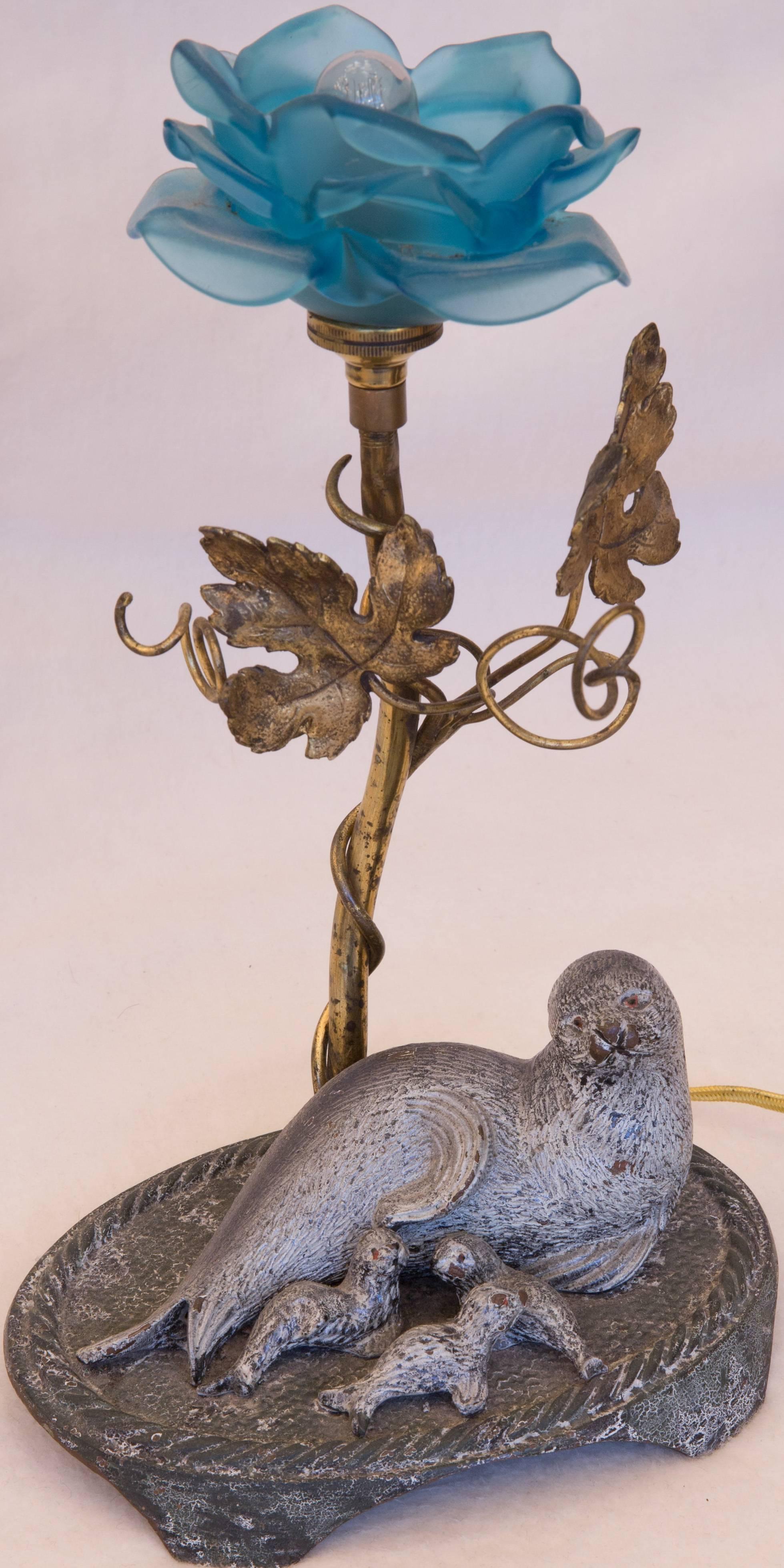 Delicately designed electric desk or table lamp with unique form having a glass blue rose with an intertwined brass branch. Cast bronze base of sea lion with her pups. Obviously a unique personal design by a maker unknown.