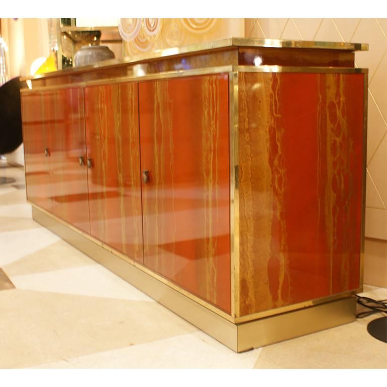 Fine sideboard by Maison Jansen, France, 1970. This four doors sideboard is red lacquered with etched effect that goes to the gold. The sideboard has the details in brass.