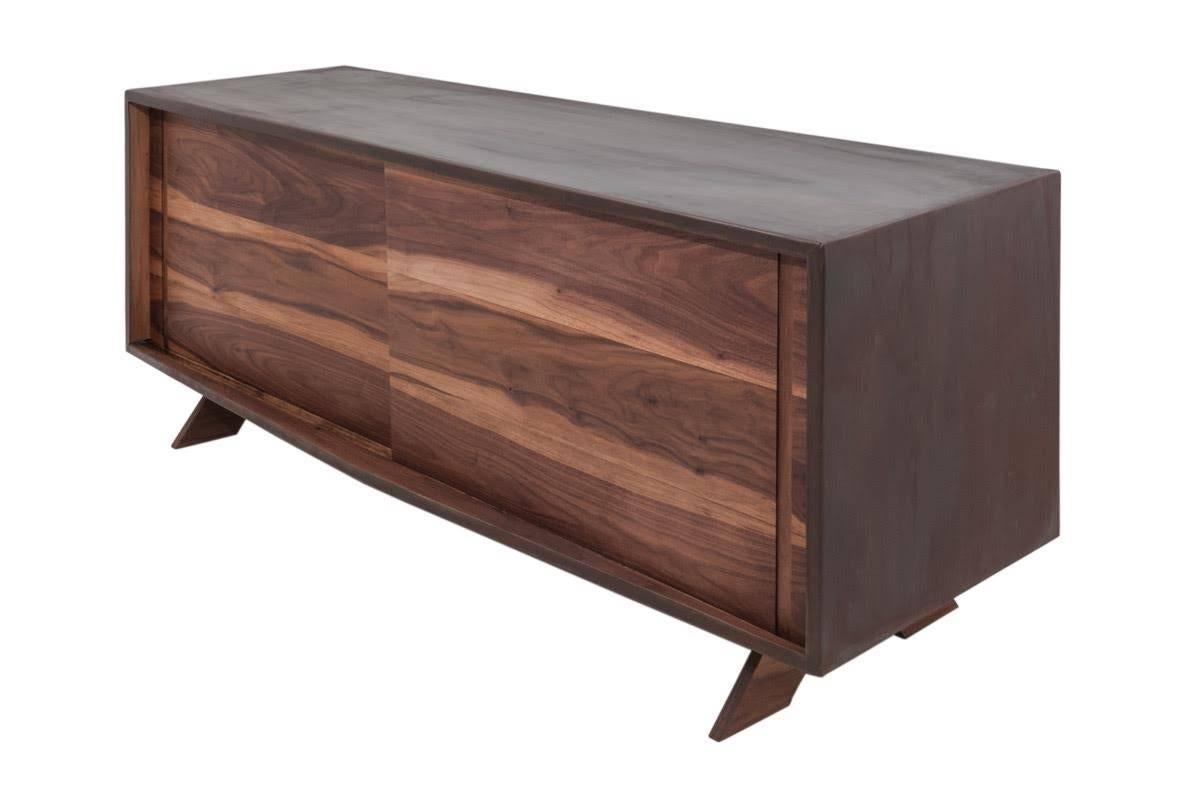 The sleek lines and precise angles of this walnut steel credenza provide the perfect frame in which to showcase copious natural wood. The innate, rustic character, warmth, supple shading, and idiosyncratic long grains—are made boldly conspicuous,