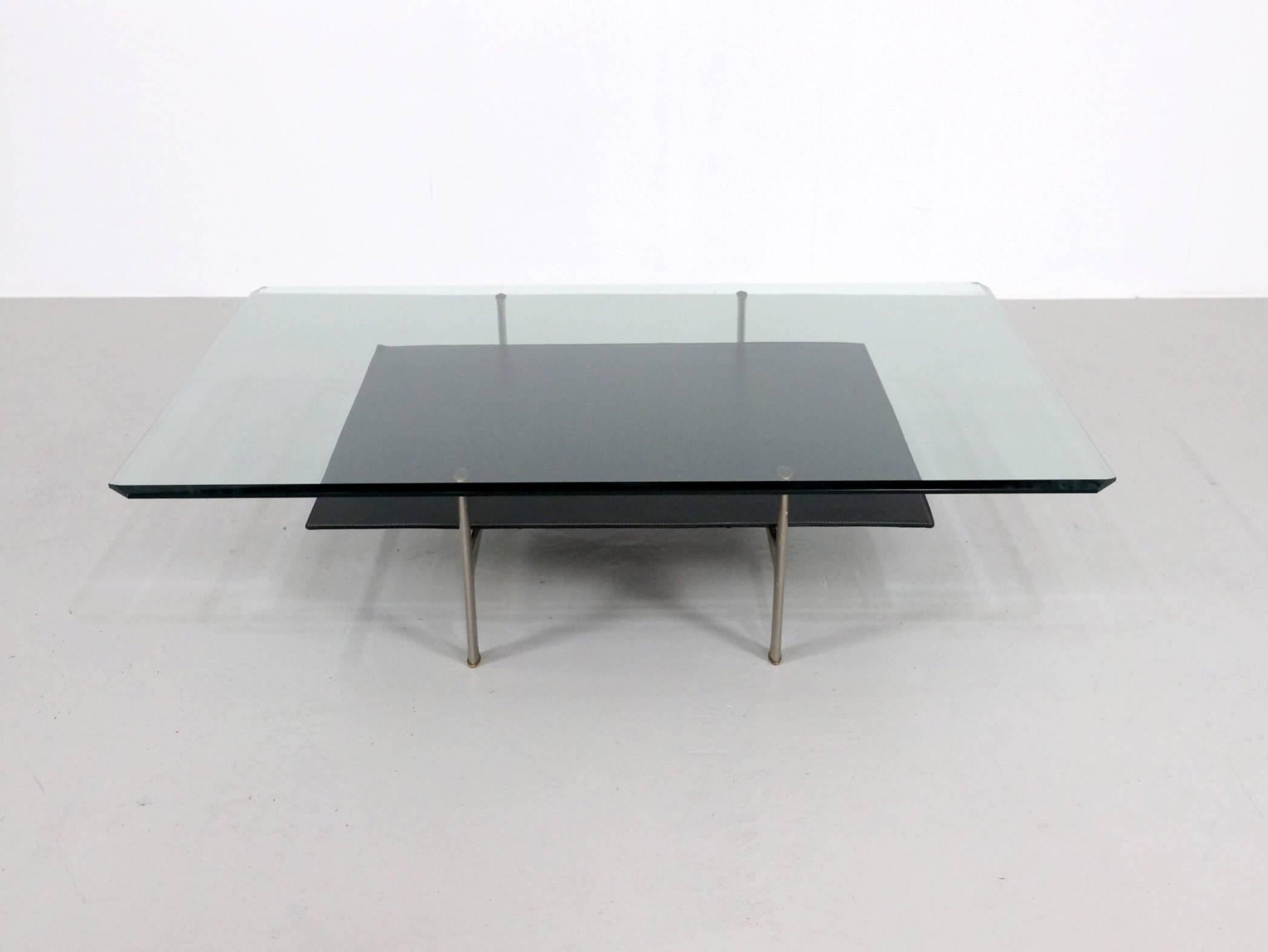 Low coffee table designed by Antonio Citterio and Paolo Nava for B&B Italia in the Diesis series. Upper top in transparent crystal glass with ground edges, the lower top is covered with black leather and a brushed aluminum frame. 
B&B Italia's