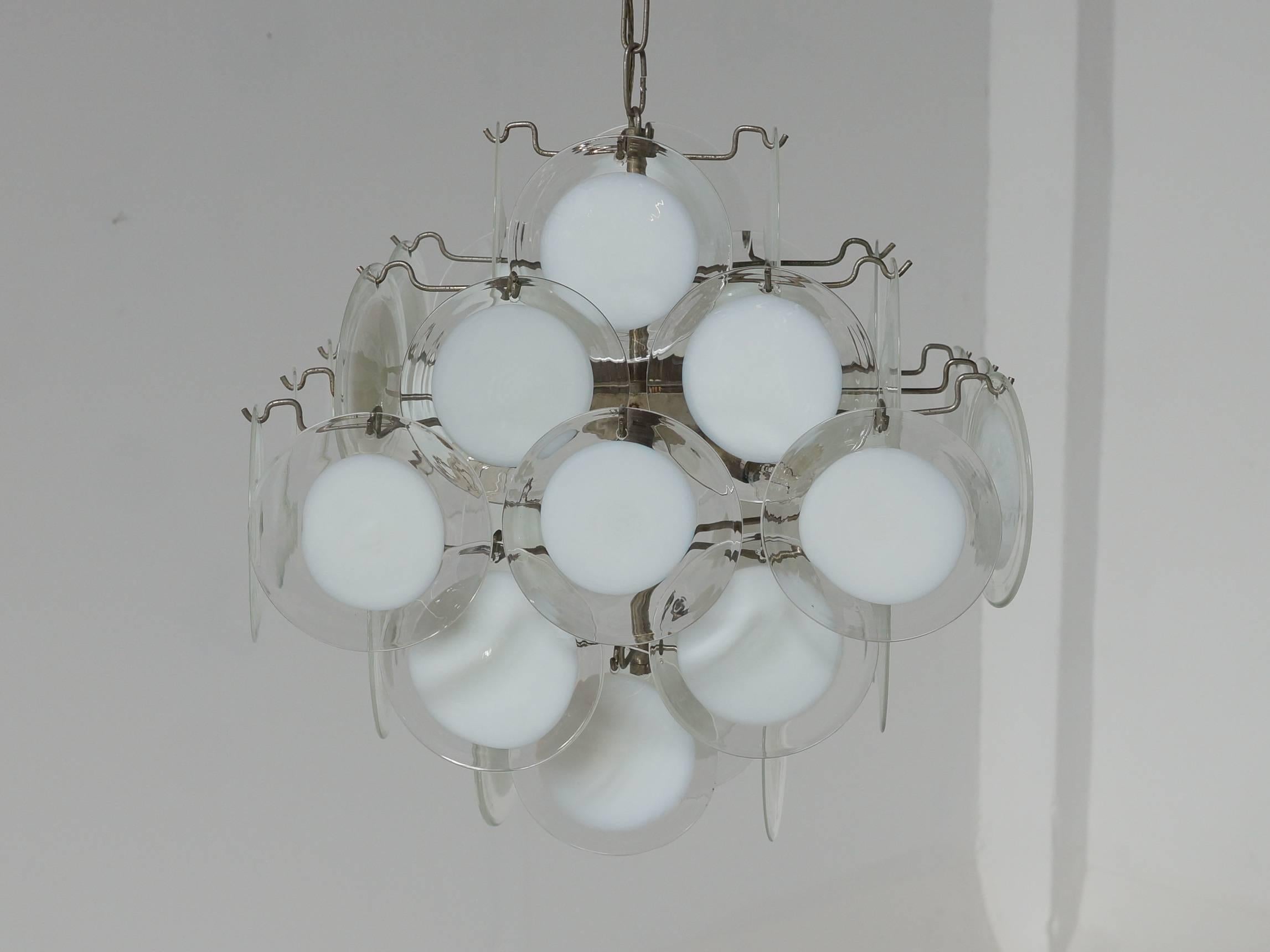 Italian Mid-Century chandelier by Vistosi. Five layers with 36 handcrafted white and clear glass discs. The chandelier lights on five small bulbs. Please feel free to contact us for extra information. Diameter 55 cm, height with chain 90 cm and