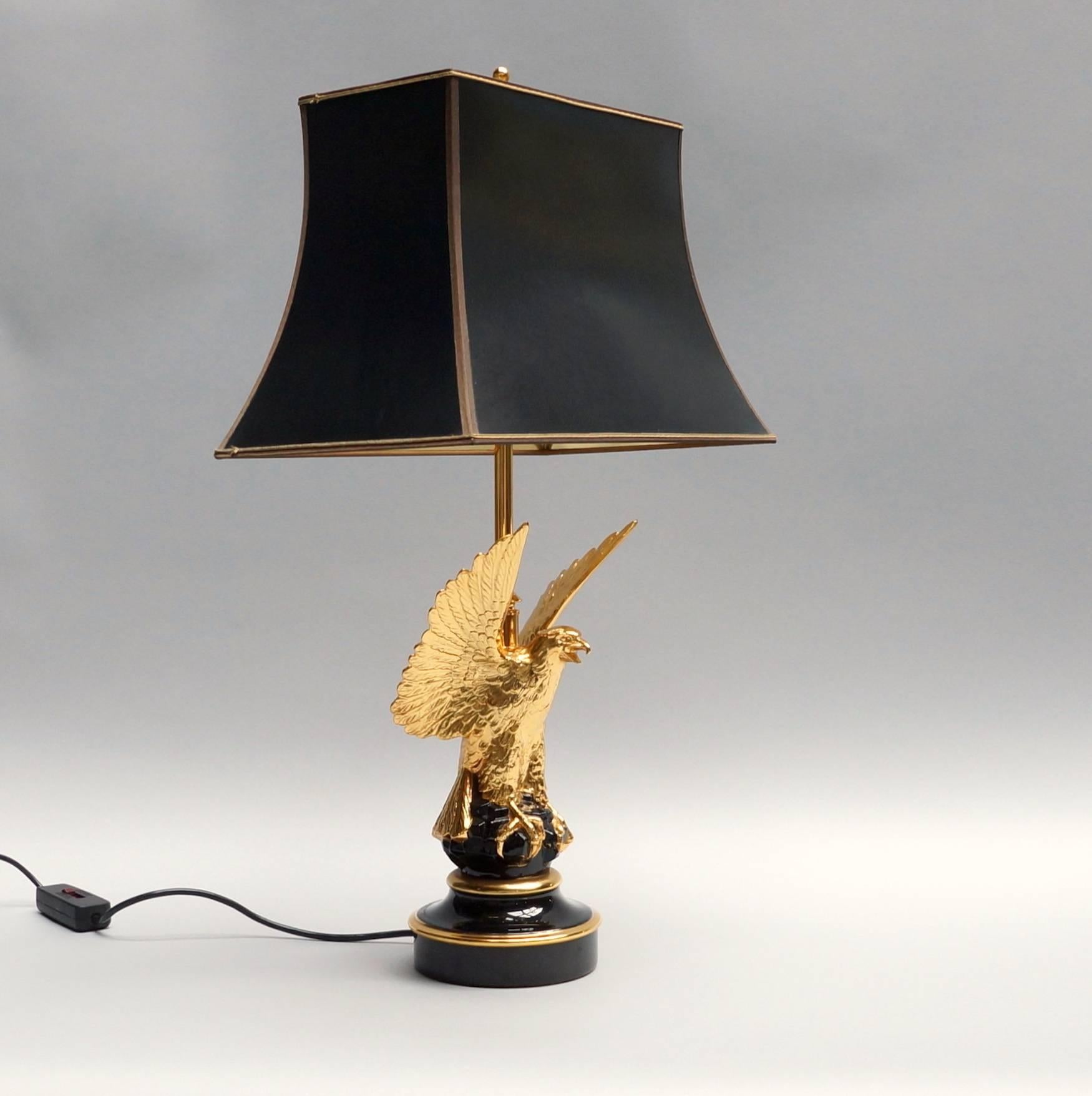 Beautiful gilded eagle table lamp in the style of  Maison Charles. The lamp has three-light bulbs and can be switched separately from each other. The black shade with golden inside creates a beautiful light.