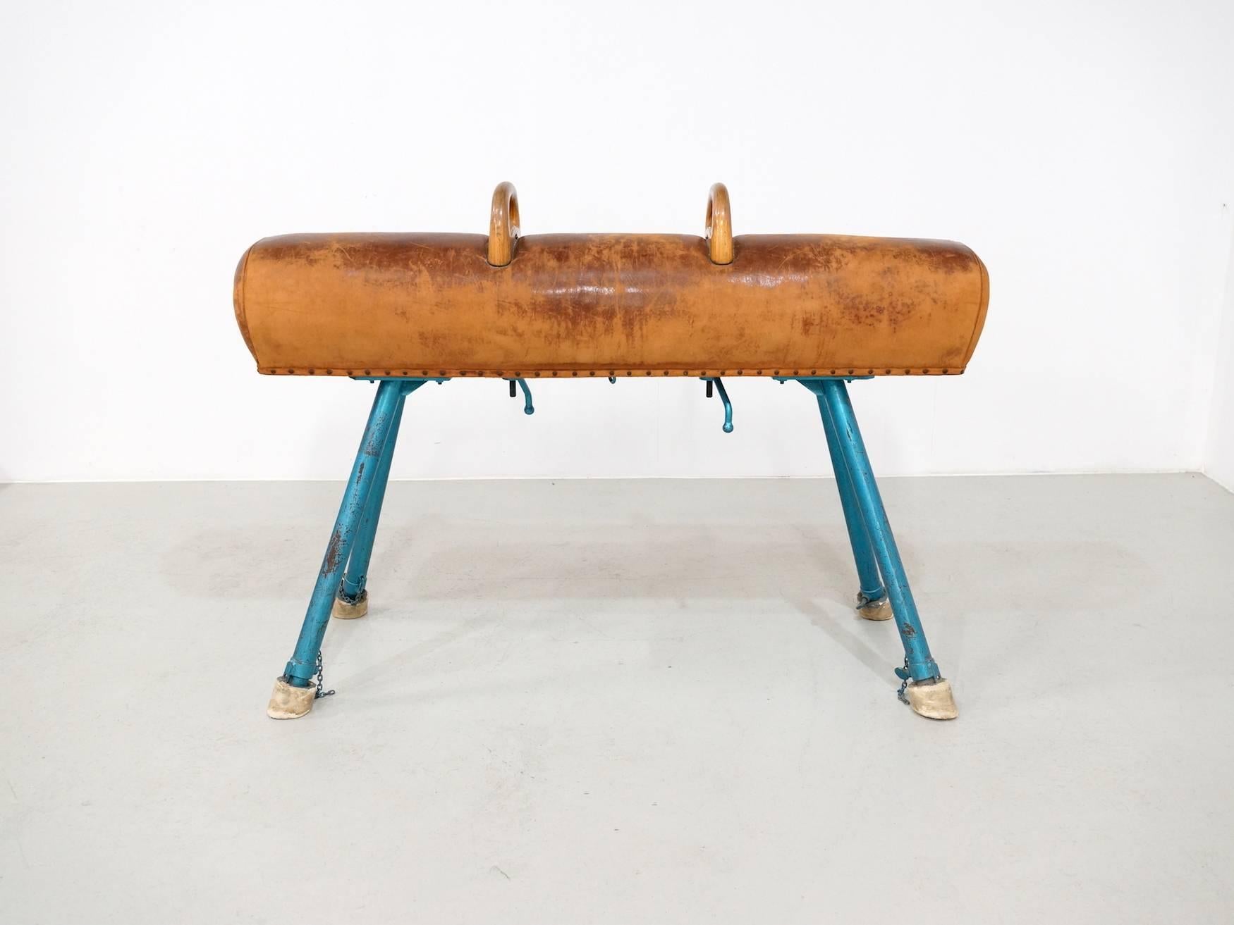 A sporty early 1950s leather, wood and iron pommel horse with adjustable legs and two wooden handles.
The Leather has a beautiful patine and is used but not broken or teared. This is how they where used in the gym:
The gymnast swings both legs in