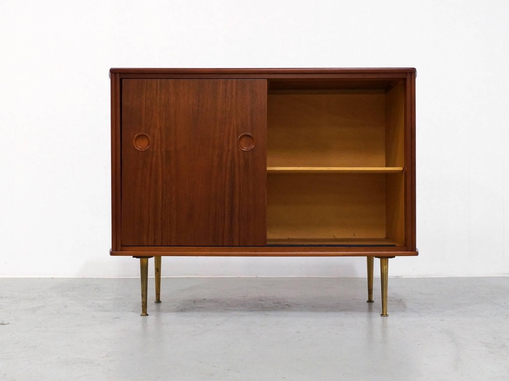Early 1960s small walnut cabinet designed by William Watting and made by Fristo in The Netherlands.
This small curved cabinet stands on brass legs and contains a cupboard behind the sliding doors. 
It's professional refinished with UV and water