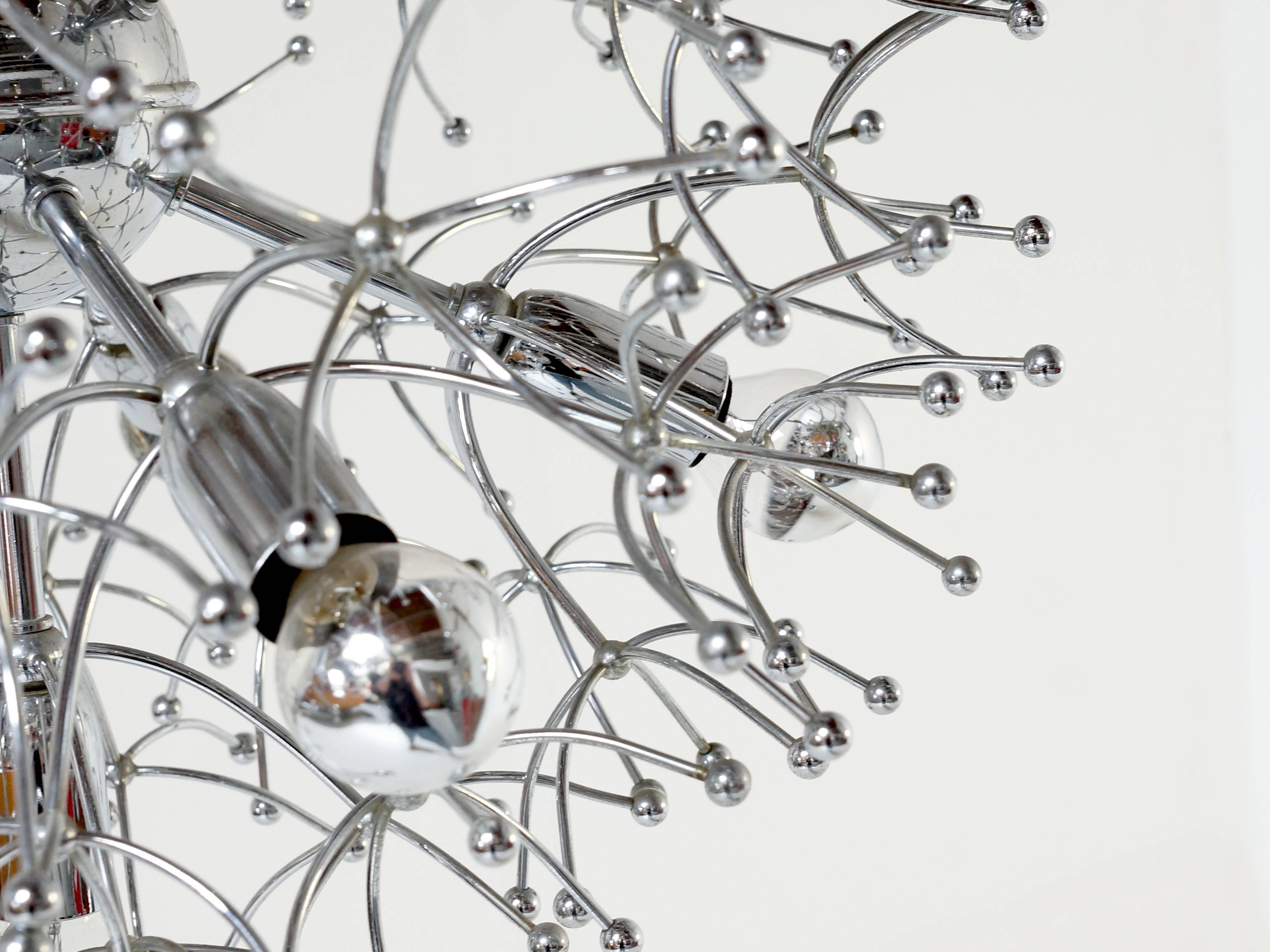 Typical Italian design from 1960s. Chandelier is shaped like a Sputnik and is designed by Gaetano Sciolari in 1960s. Chromium-plated metal with between the lamps a spider web on chrome. The lam is fitted with 11 mirror bulbs E 14. 
On request you