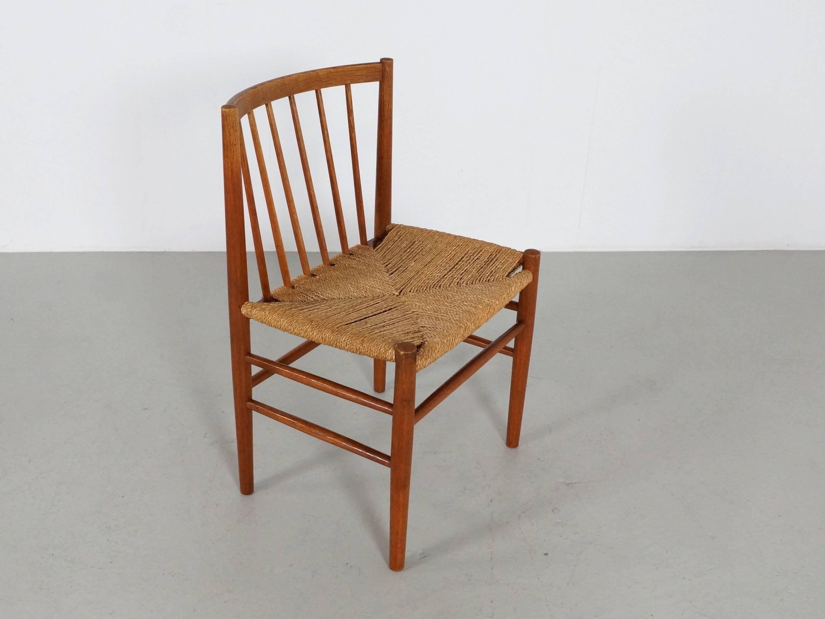 A set of four Danish oak dining chairs designed by Jørgen Bækmark for FDB Møbler 1950s with a paper cord seat, a curved backrest and six vertical dowels pitched at an angle for support and comfort.
The finish and the woven paper cord seats are in