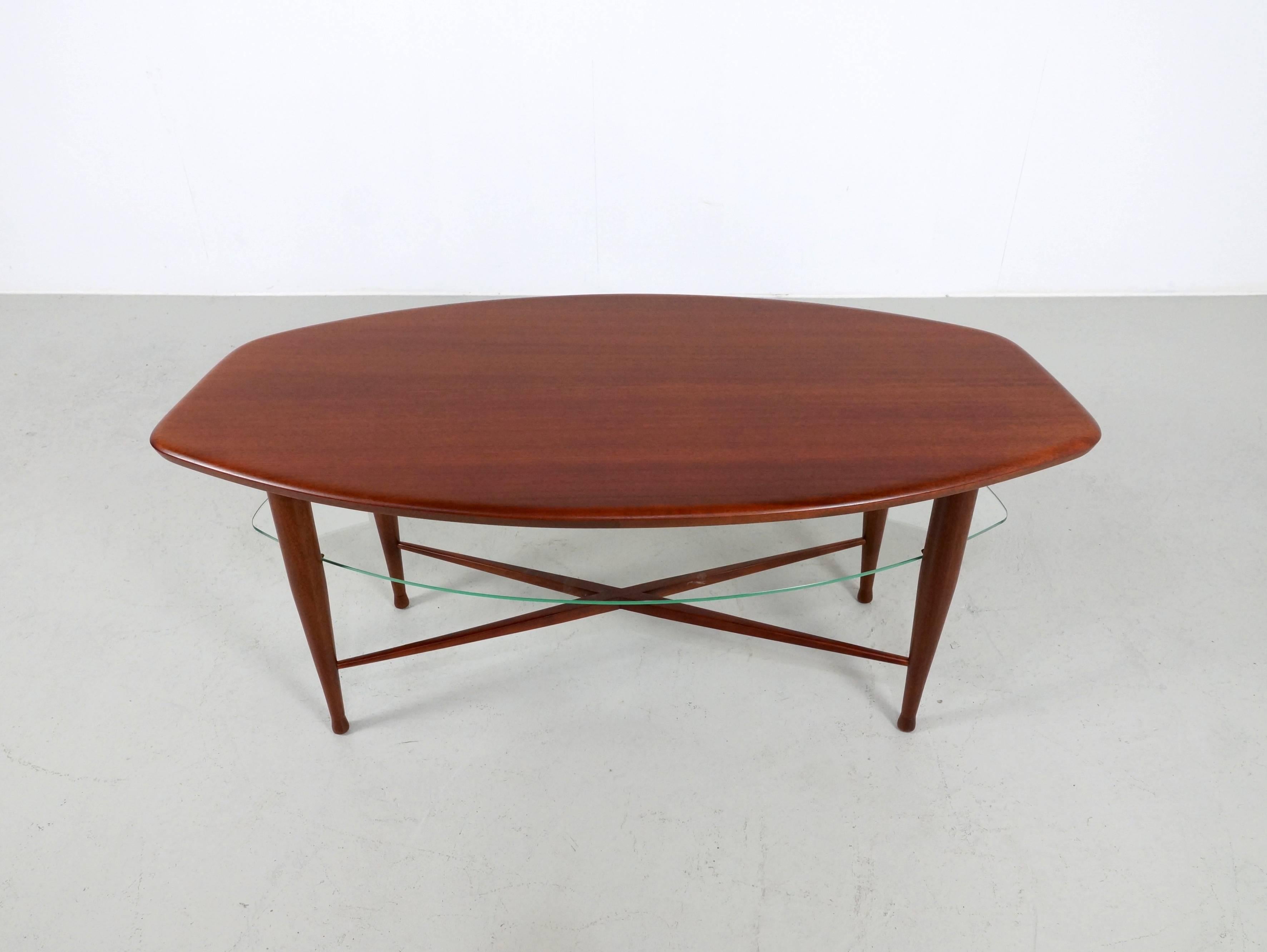 Beautiful but rare free-form coffee table in teak. Under the top is in the same shape as the top a glass Magazine or storage shelve. 
The table stands on beautiful tapered legs ending in a sphere.

The table is professional refinished with water