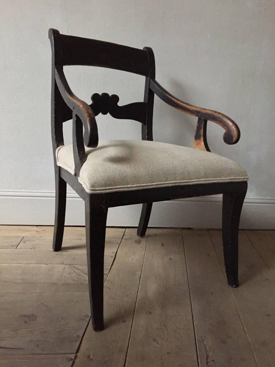 fauteuil scandinave du XIXe siècle en hêtre et linnen. Ce charmant fauteuil a été fabriqué en Suède dans le style néoclassique local. Comme il est d'usage dans cette région, la chaise est peinte avec des pigments naturels. La couleur noire est