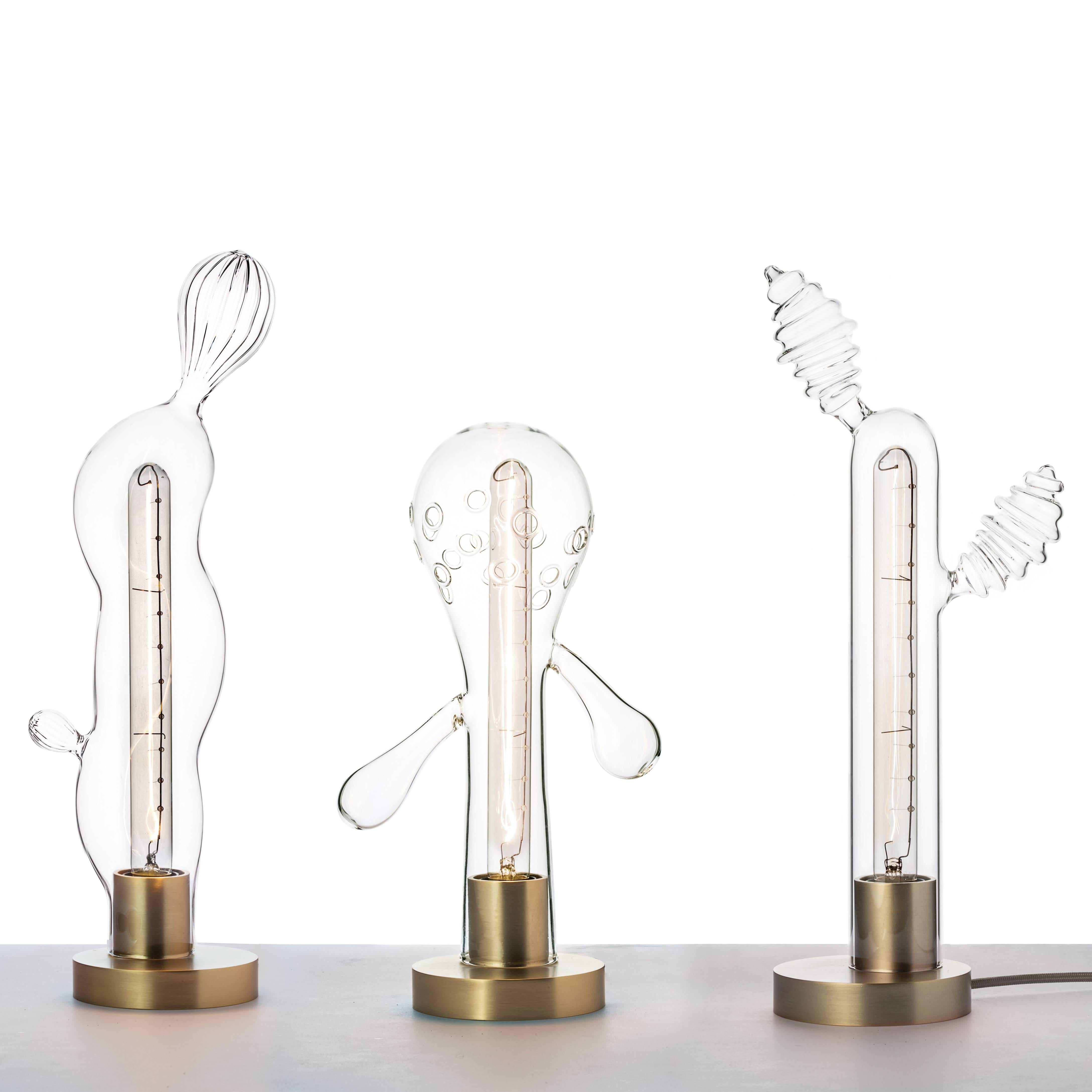 Transgenic lights de Matteo Cibic est une série de trois lampes de table. Les structures de verre s'inspirent des formes du règne végétal, reconnaissables malgré le processus de mutation génétique qu'elles semblent avoir subi. Le processus de