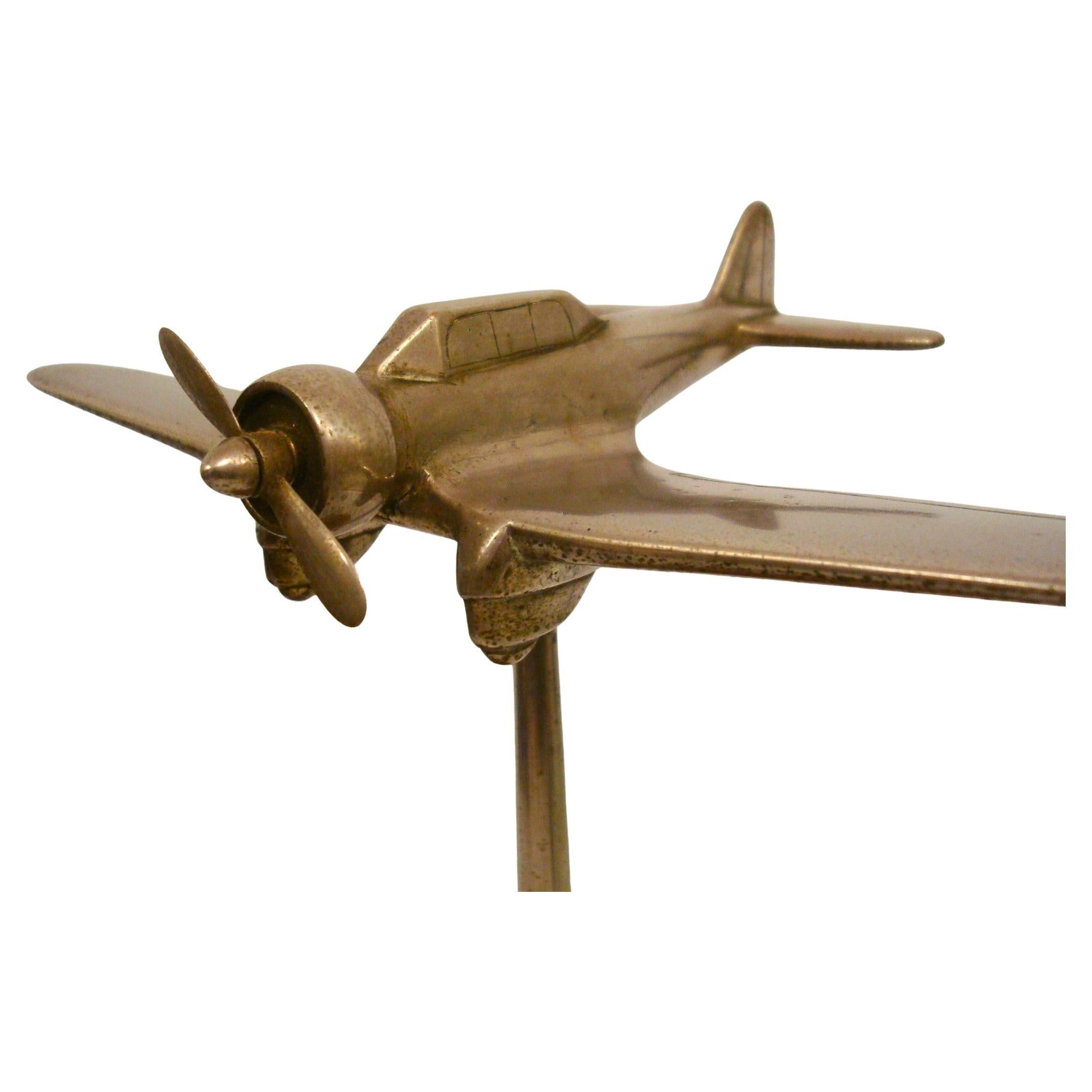 Maquette d'avion de chasse de bureau Art déco des années 1940
Modèle réduit d'avion monté sur un support de globe en bois. L'avion est en métal et est représenté en vol avec son hélice à l'avant. Le globe en bois est sphérique et présente une