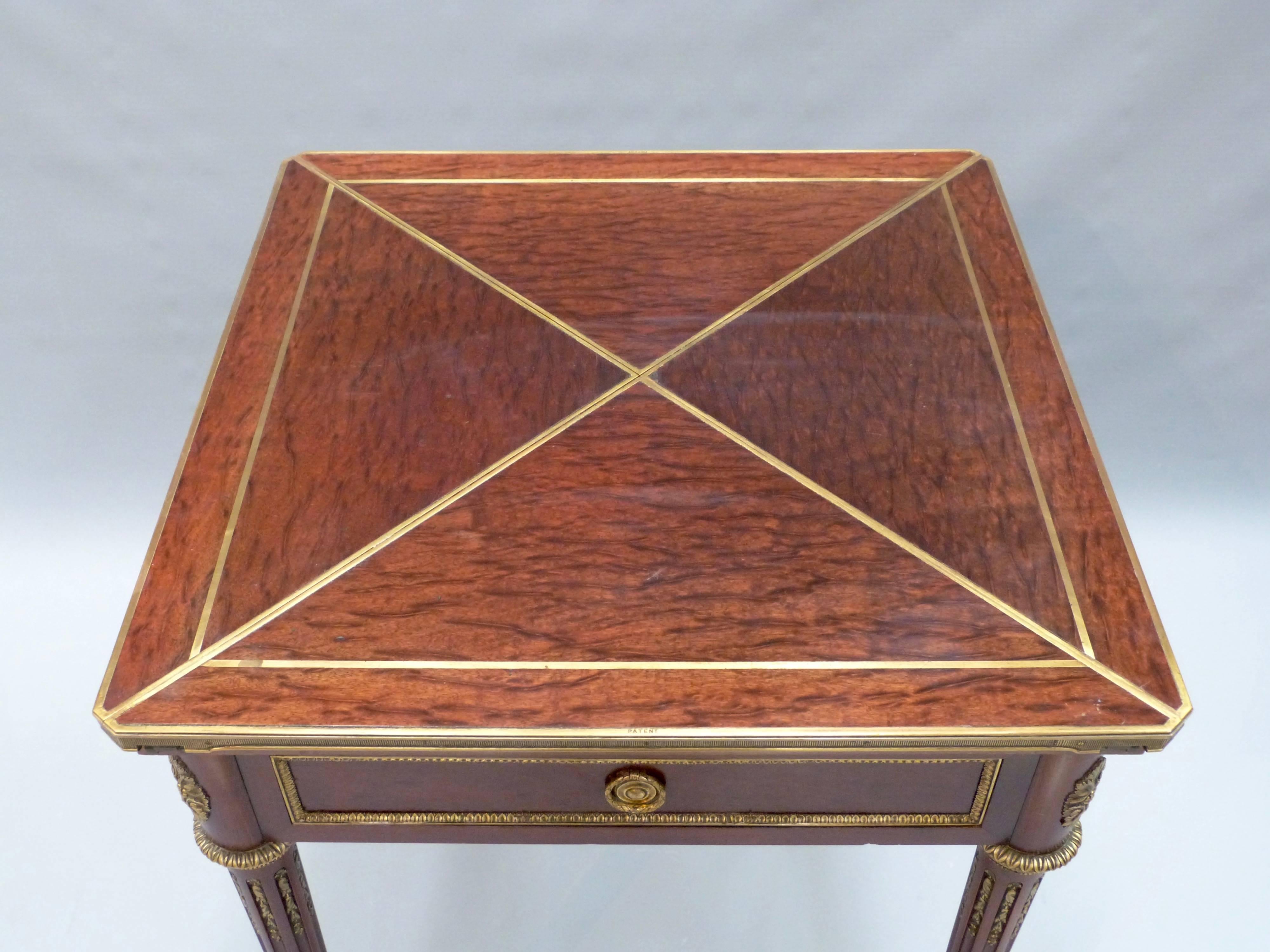 A French Louis XVI style envelope card table with gilt mounts to the turned fluted legs and top with plum pudding mahogany panels, circa 1890.