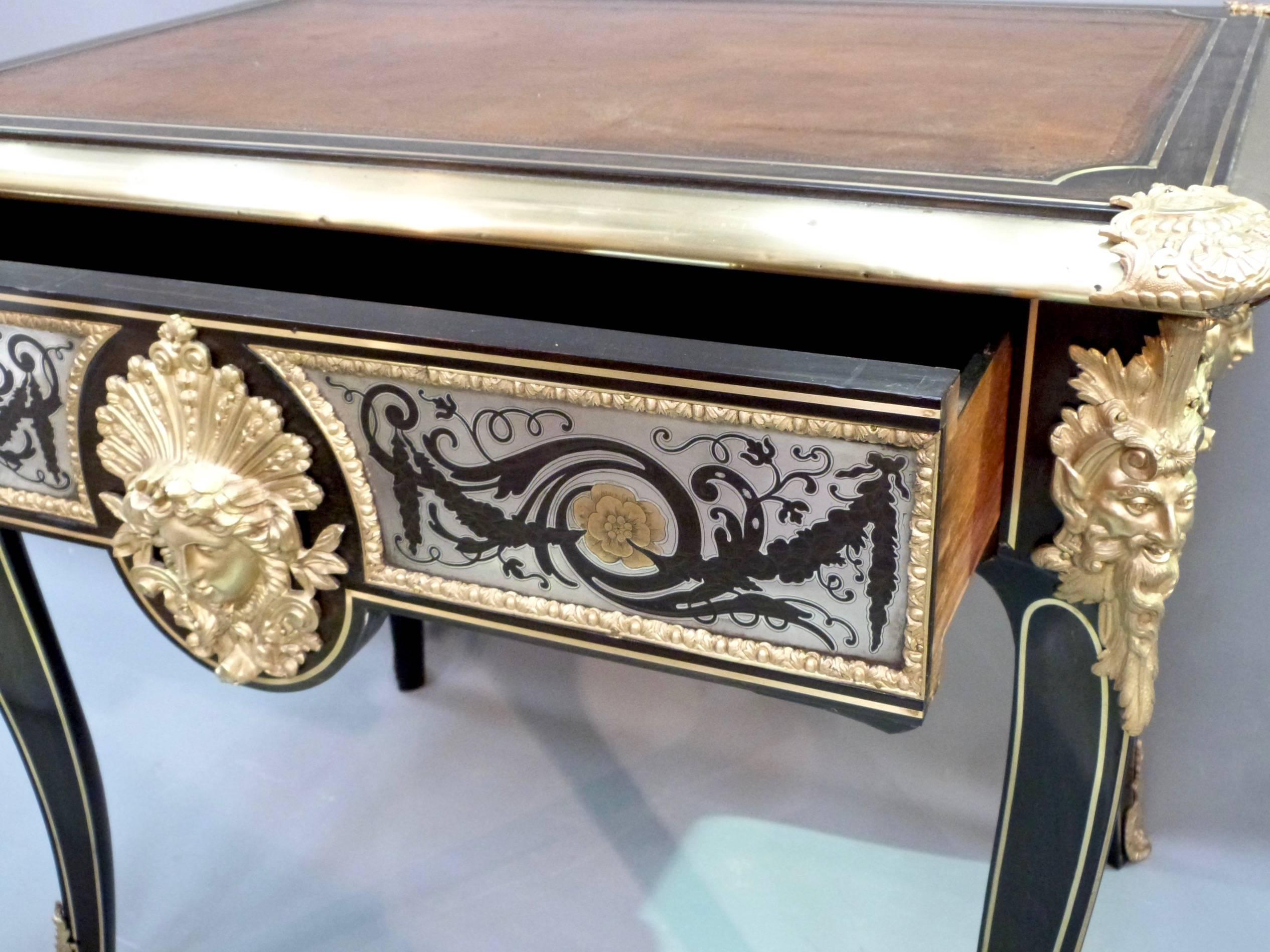An outstanding 19th century ebony, gilt bronze and pewter writing table. The table features wonderful gilt bronze masks in the French Regence style. Each side has pewter inlaid panels swags and brass flowers. The piece stands on brass inlaid