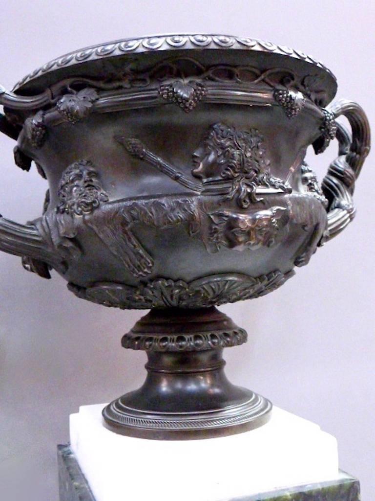 A Large 19th century French bronze reduction of the Warwick vase, mounted on a green and white stepped marble plinth.