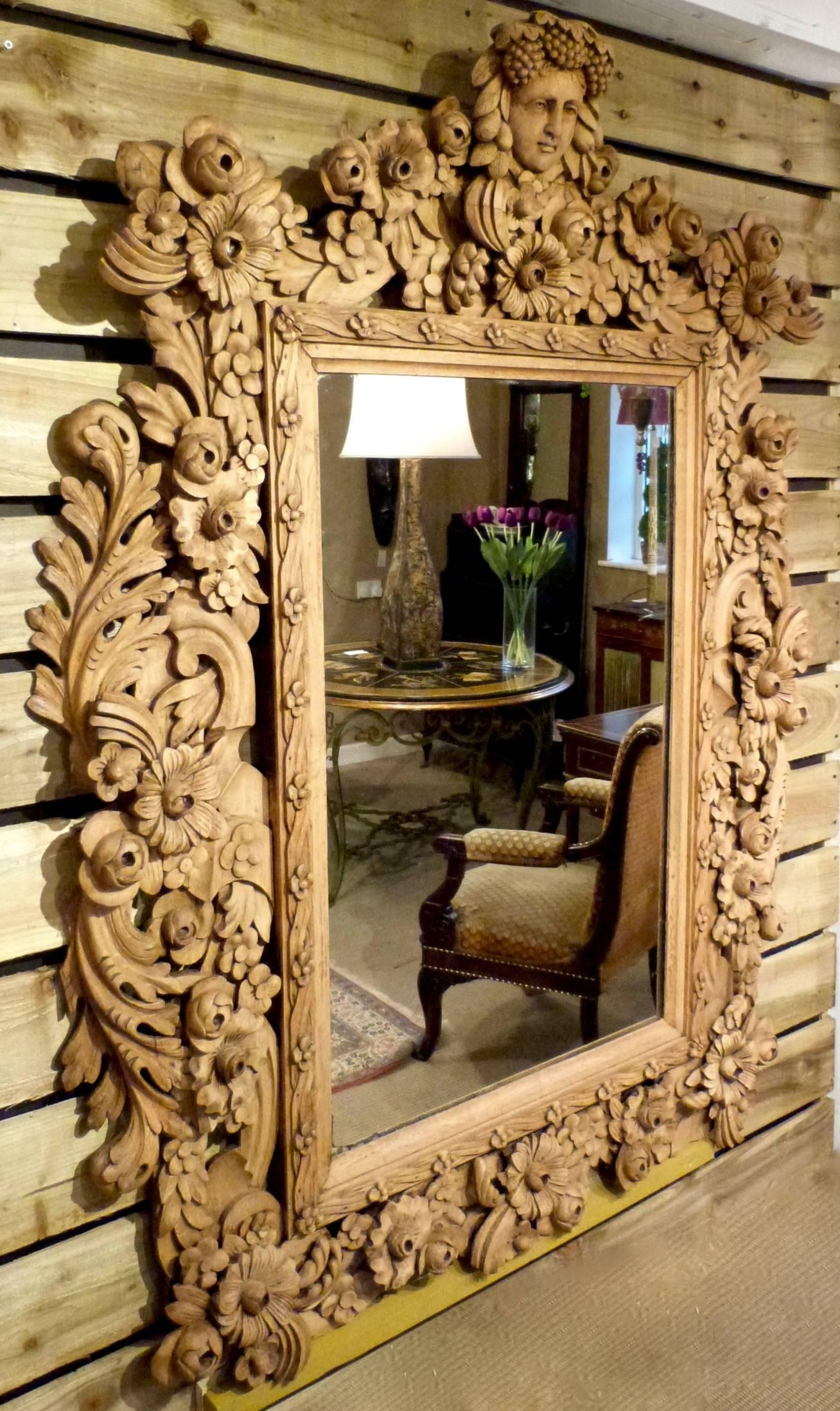 An outstanding large and extremely decorative continental carved and bleached oak wall mirror. The frame carved with swags and vine decoration the pediment with a carved head of Bacchus.