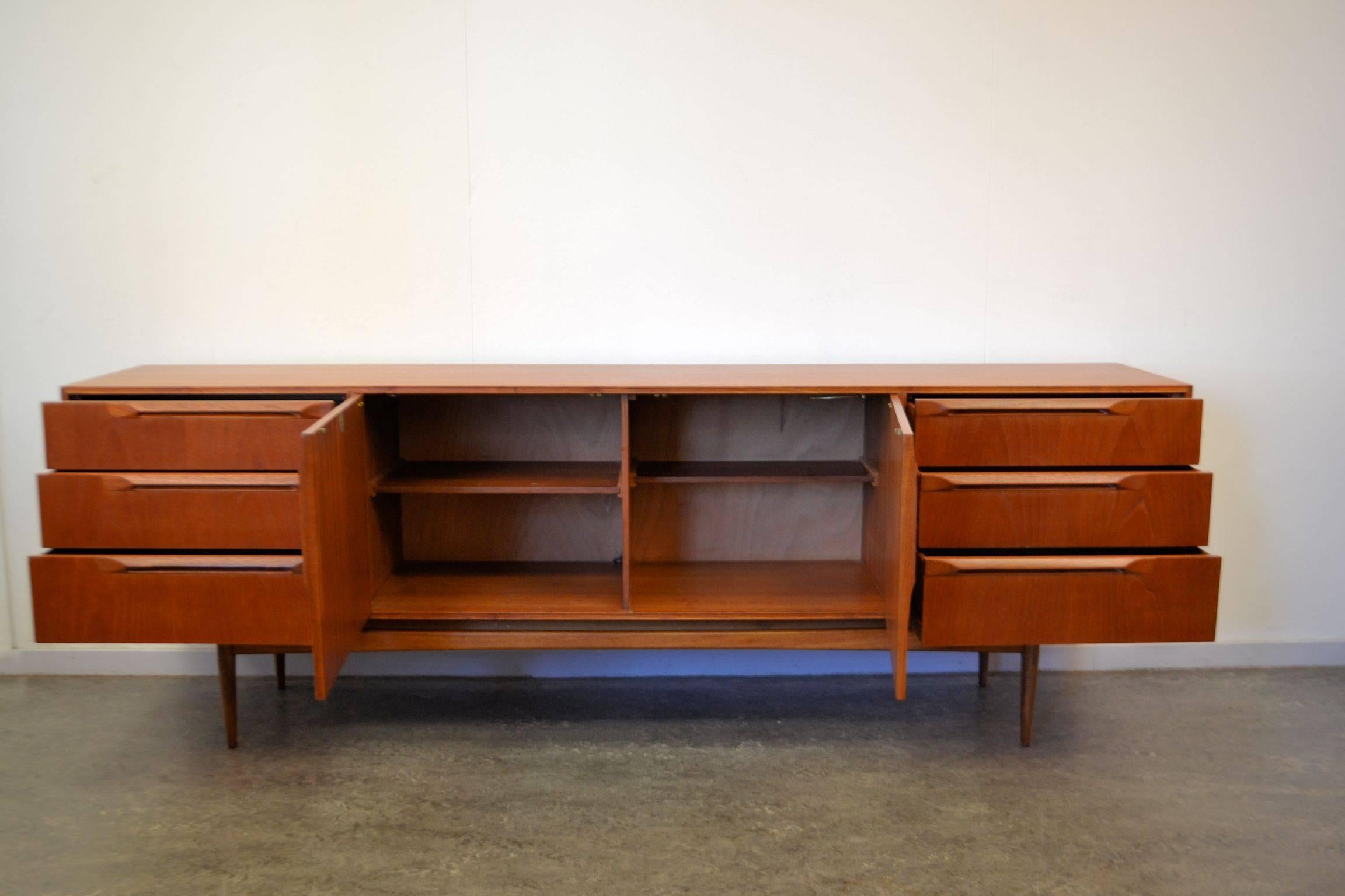Mid-Century Modern teak sideboard produced during the 1950s-1960s in Scotland by McIntosh Furniture.
This extra large sideboard has three drawers on each side with beautiful shaped handles. In the middle there are two doors behind which you can