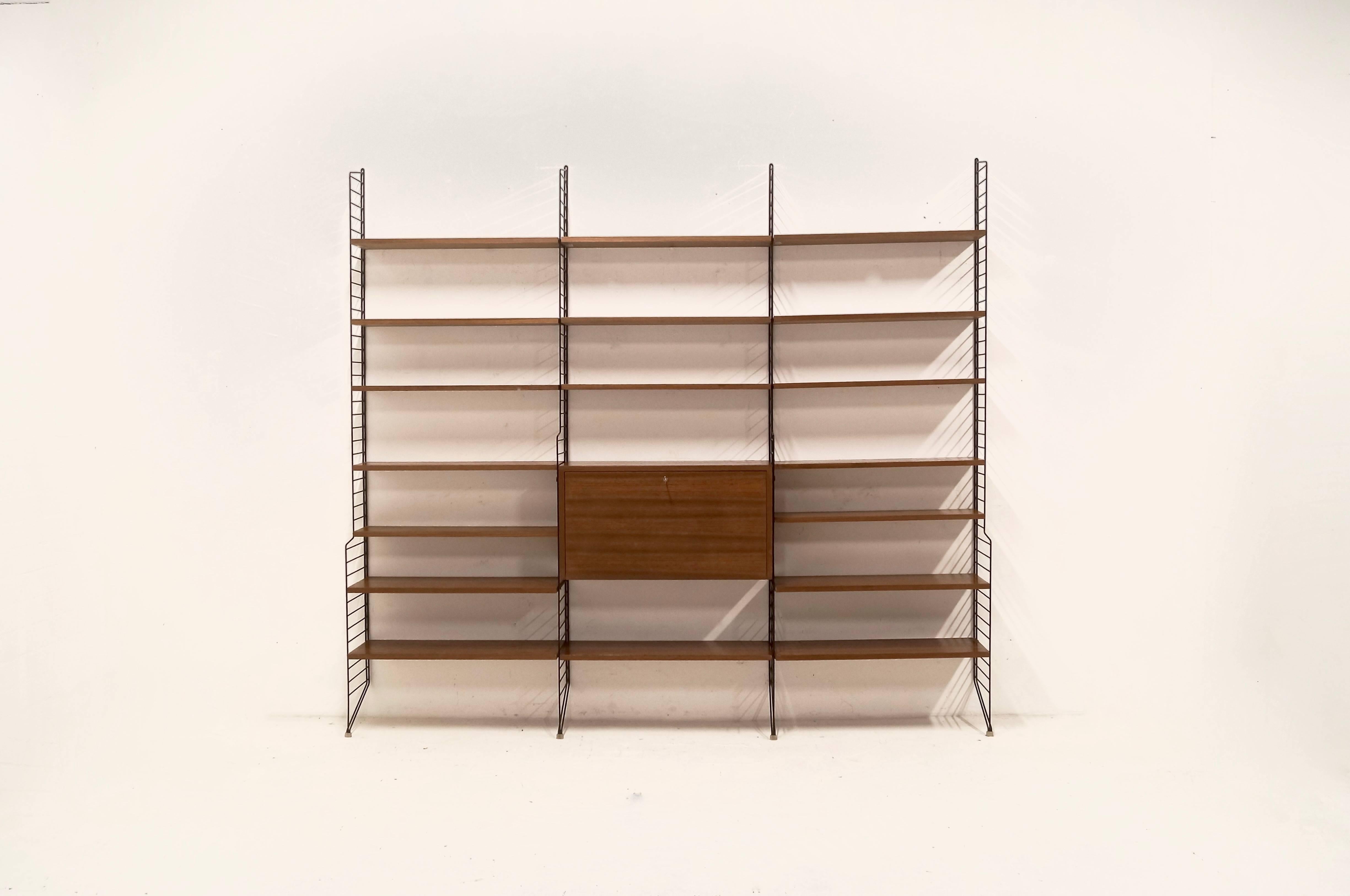 Mid-Century modulair free standing Nisse String shelving system designed by Nils Strinning for AB Sweden, 1950s. Shelves are made of teak and the system includes a desk or secretary cabinet.