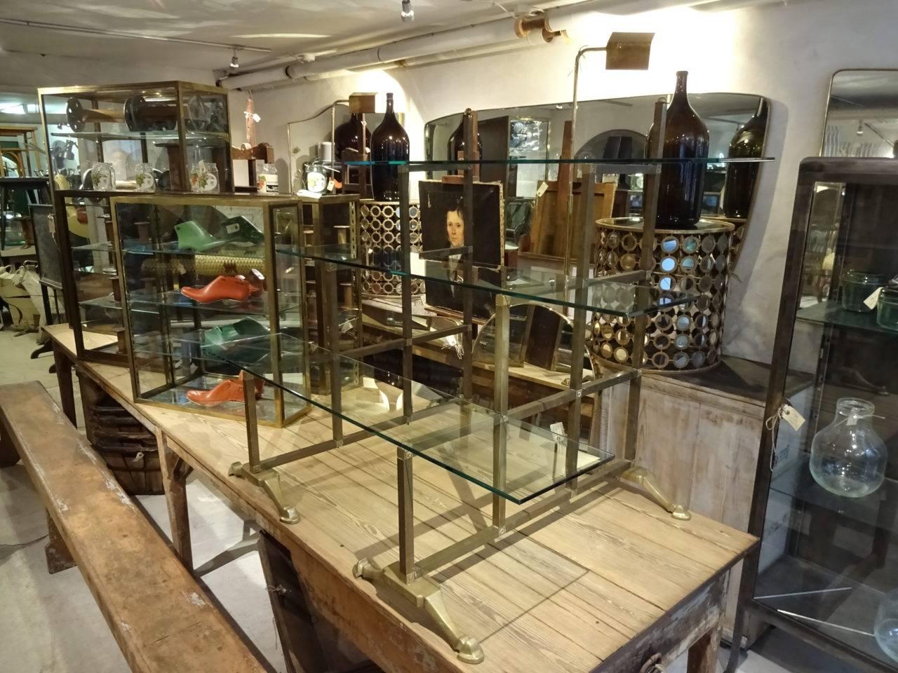 Lovely Italian solid brass ètagère, previously part of a Milanese shoe boutique’s inventory. The display unit has three thick glass shelves and wonderful gilt metal feet. Super floral decorations on the framework. Perfect display furnishing for your
