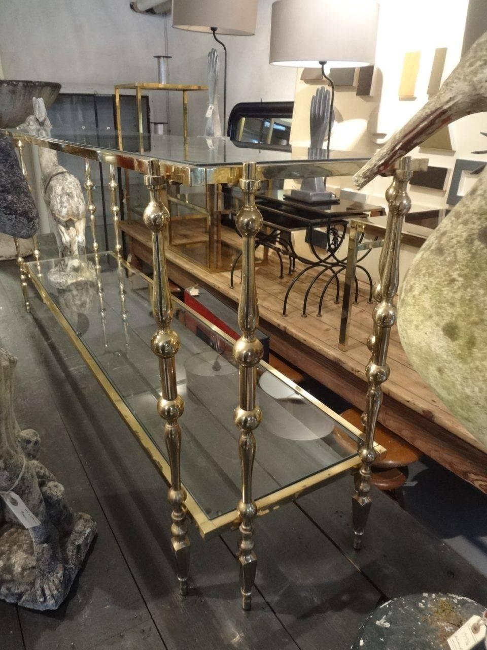 Stunning French and beautifully detailed brass framed console table. Two glass shelves and decadent elegant double legs on each corner.